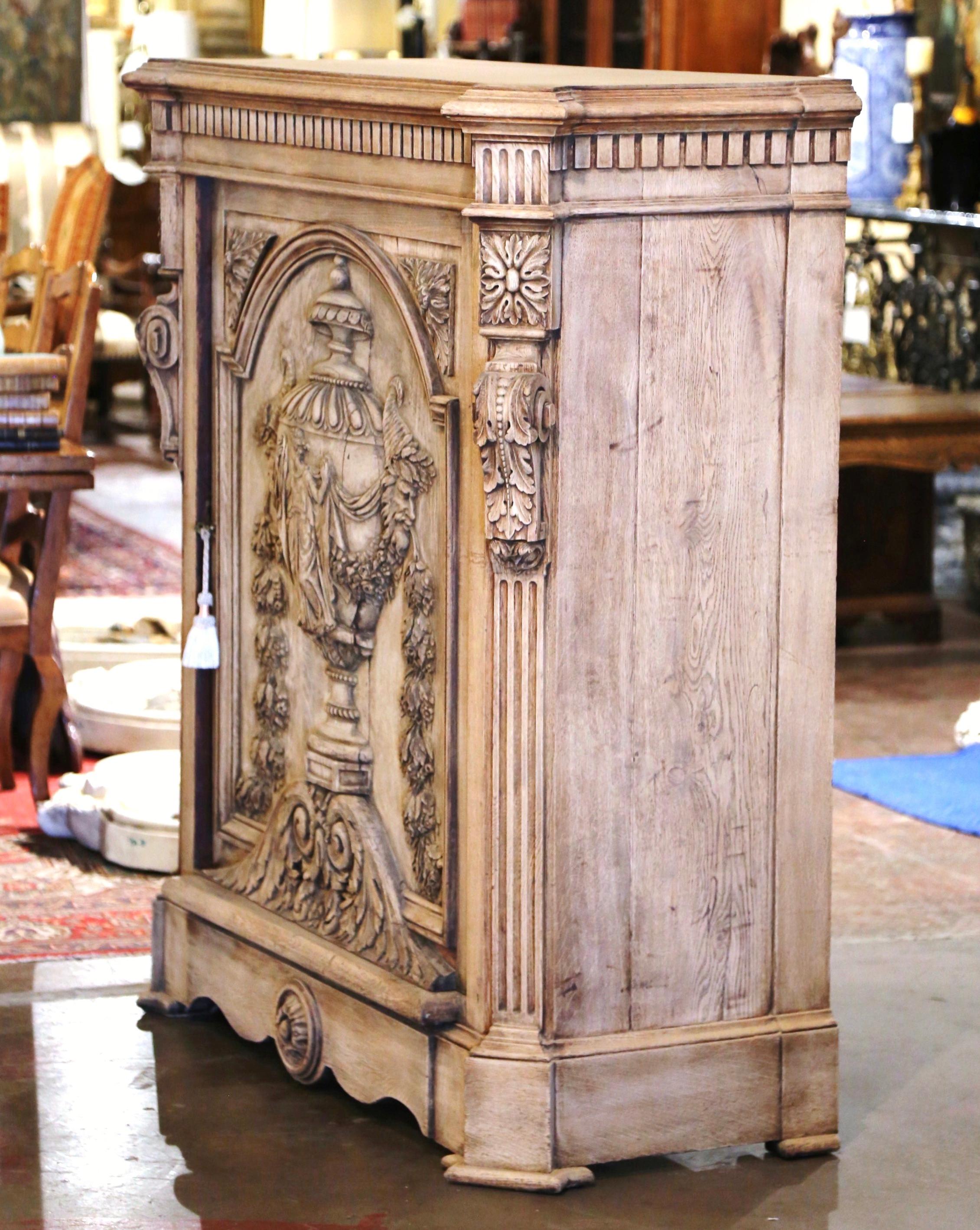 Crafted in France, circa 1870 and built of oak wood, this single door confiturier (or jelly cabinet), stands on bracket feet over a scalloped apron decorated with a center floral medallion. The antique cabinet features a large door with arched top,