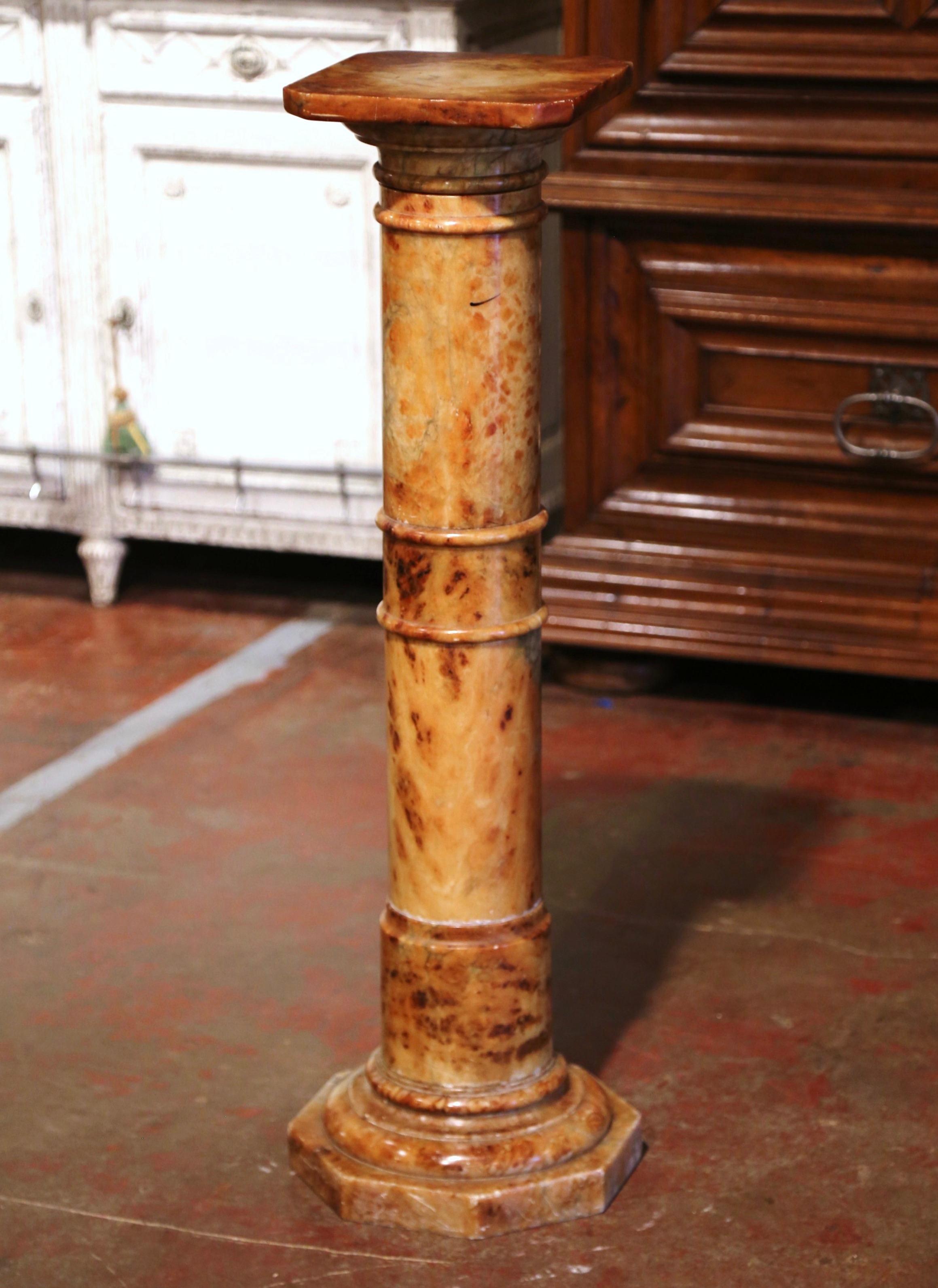 This elegant antique pedestal was crafted in France, circa 1870. Made of variegated marble, the display piece stands on a sturdy octagonal double plinth base over a round stem embellished with carved decor throughout. The surface is dressed with a