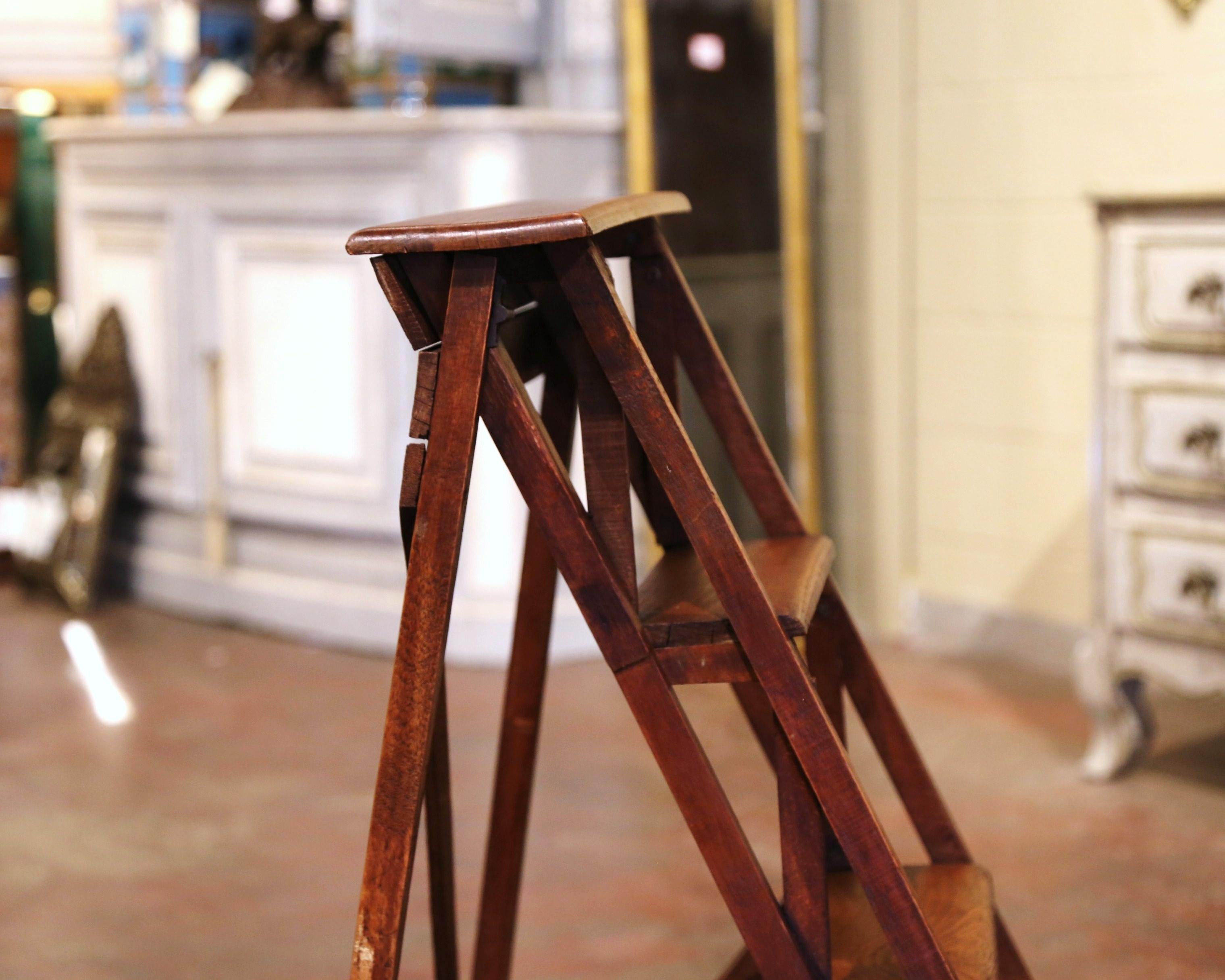 Crafted in Lyon, France circa 1880 and made of walnut, the stairs features four graduated steps to one side and connected to the opposing support with a wooden and metal action folding mechanism. Practical and useful, the ladder can folded and put