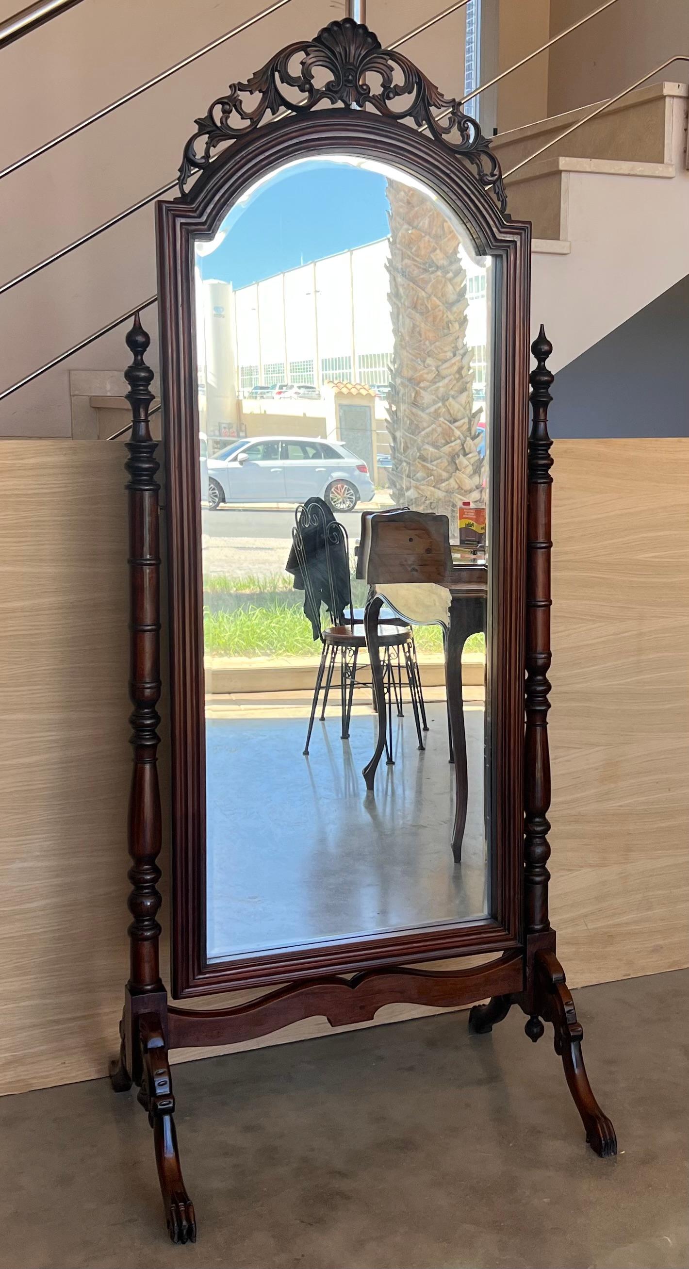 A large 19th century French Napoleon III chevalet, or cheval mirror, made of solid walnut. Turned columns and finials and nicely carved details on the scroll form legs and shell form crest at the top. Mirror has old silvered patina. Excellent