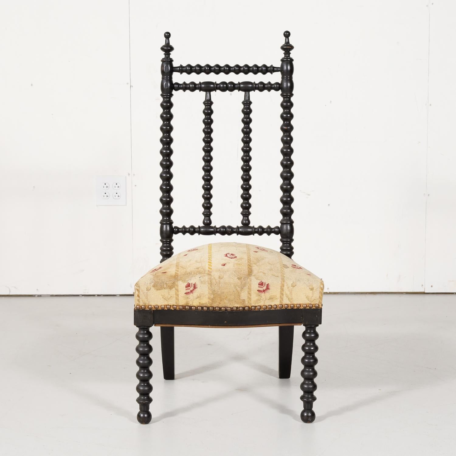 19th century French Napoleon III ebonized bobbin nursing side chair circa 1850s, having a turned wooden bobbin frame with turned finials above an upholstered seat, raised on front bobbin legs and saber back legs. Low seated chairs like these were