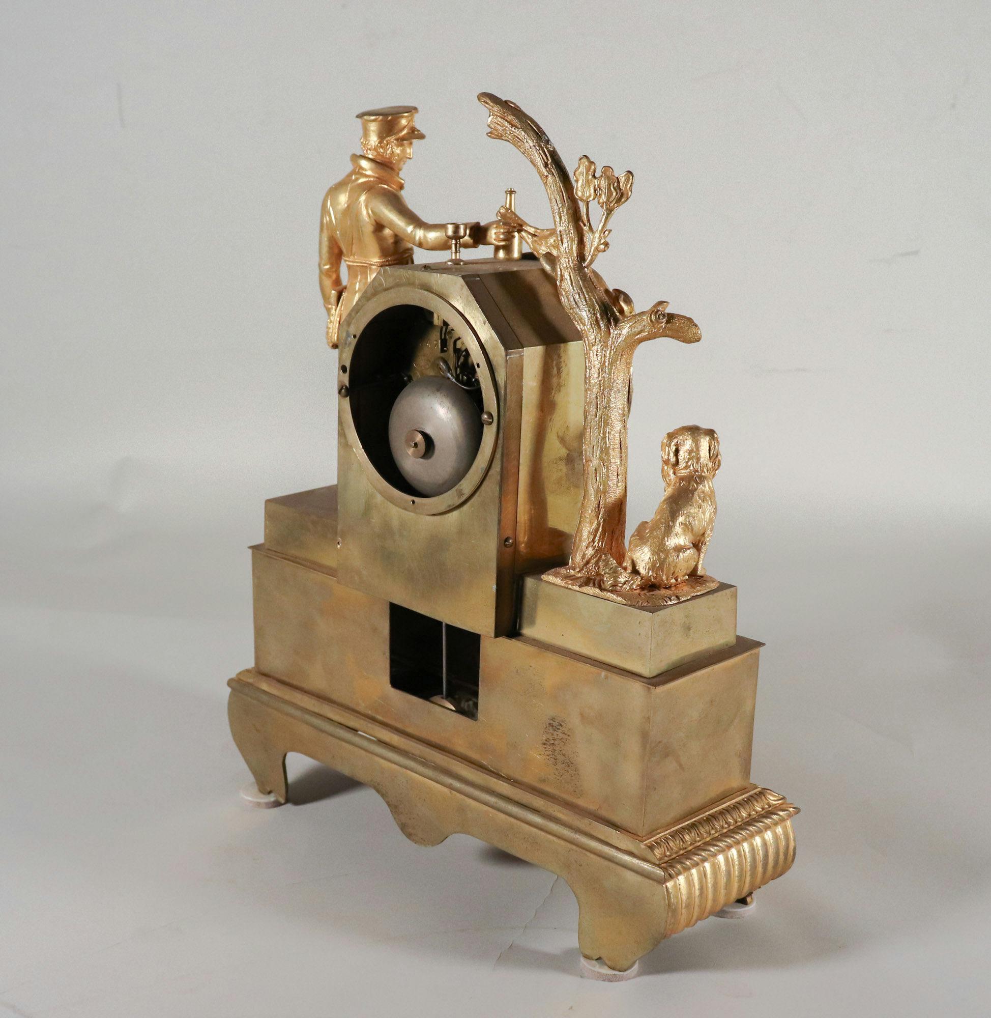Questo orologio da caminetto francese del 1850 circa presenta uno splendido design figurativo realizzato in bronzo dorato. Raffigura un cacciatore con un coniglio infilato nella curva superiore della cassa dell'orologio. L'uomo è vestito secondo la