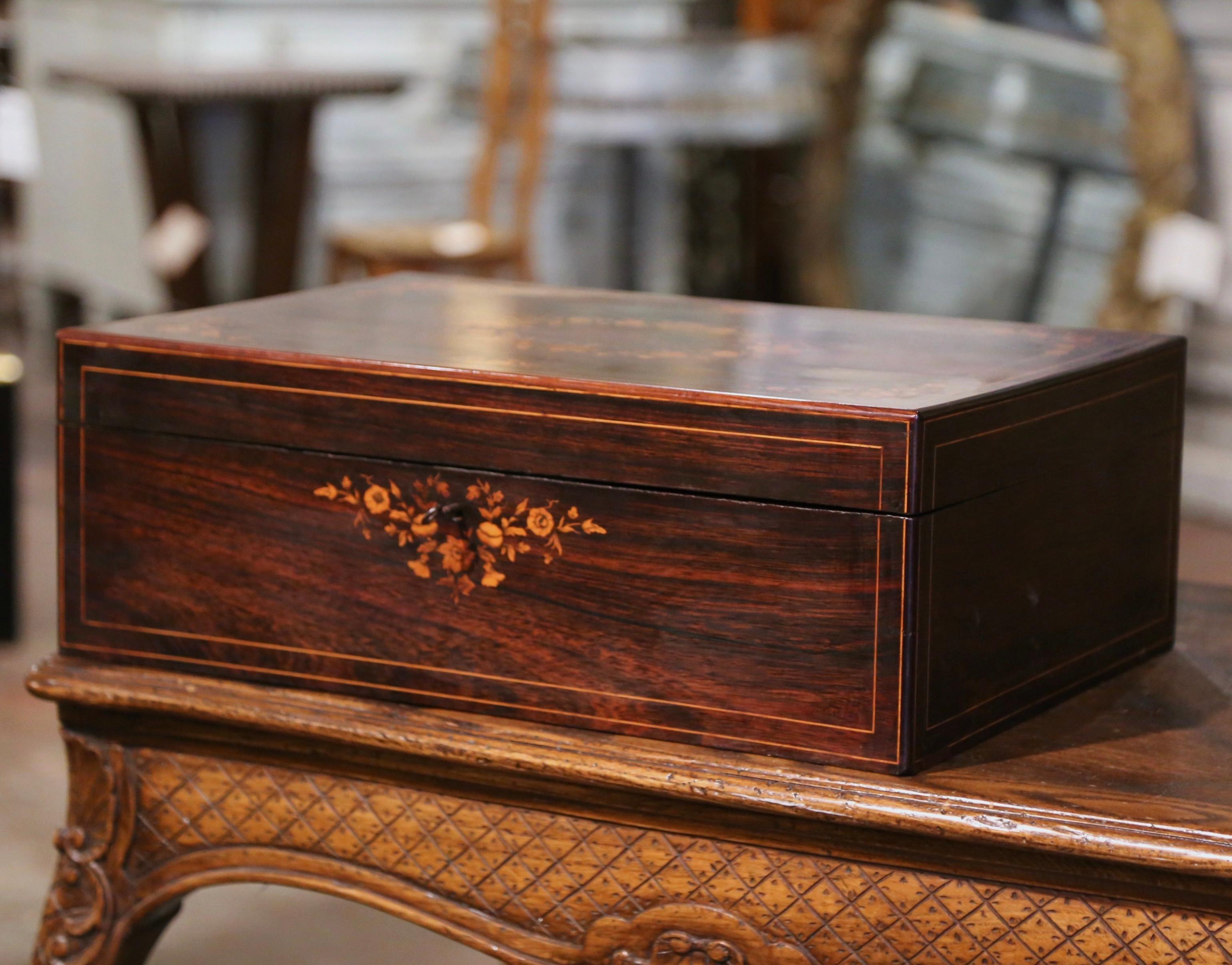Decorate a coffee table or a shelf with this elegant antique box. Created in France circa 1880, the rectangular cabinet is decorated with elegant floral inlaid work in each corner and embellished with a central foliage medallion. Opening the box, it