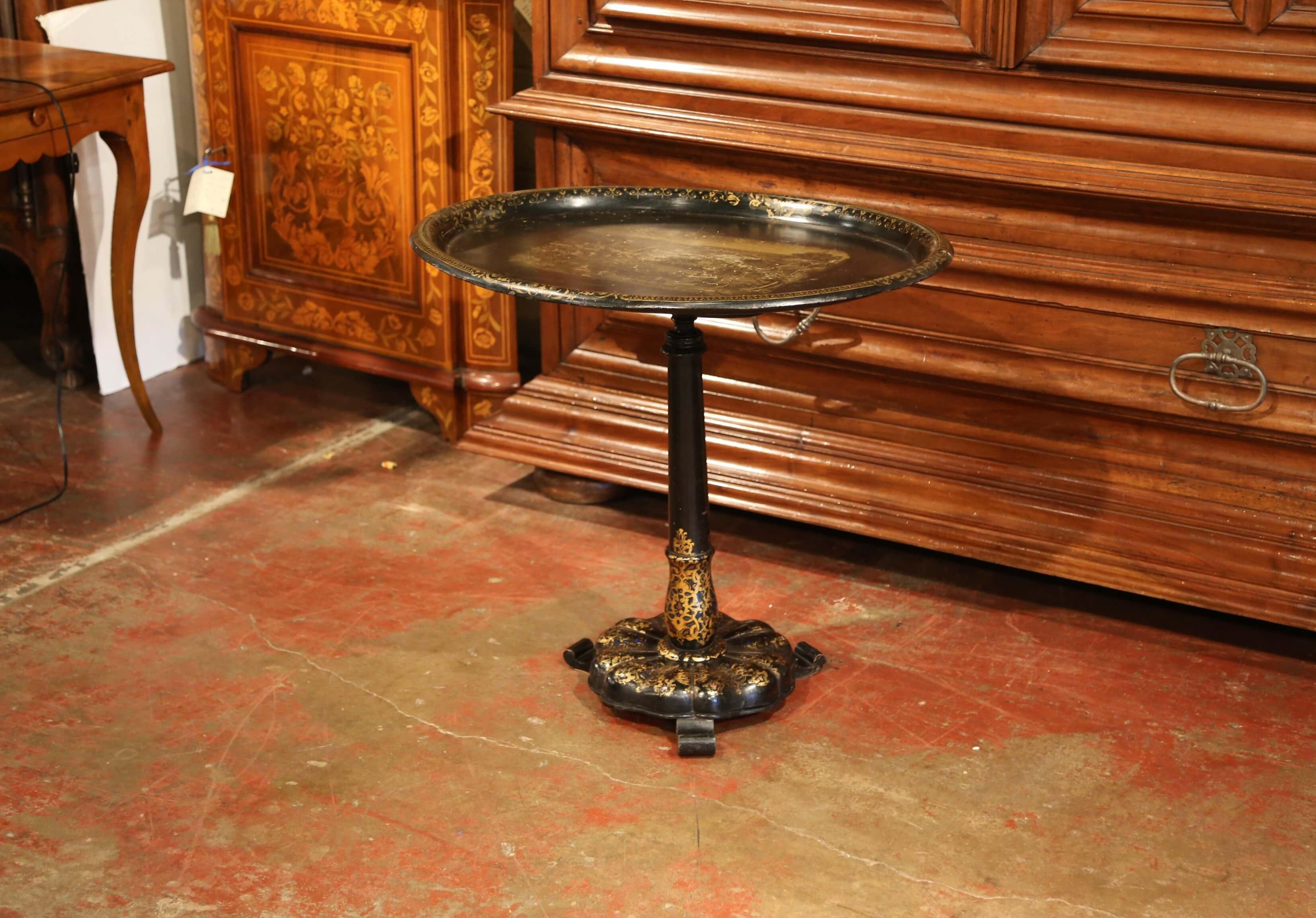 This elegant antique side table was crafted in Paris, France circa 1870, the occasional table features a blackened wooden pedestal base embellished with hand painted gilt accents, and a tole tray surface with hand painted pastoral scene medallion in