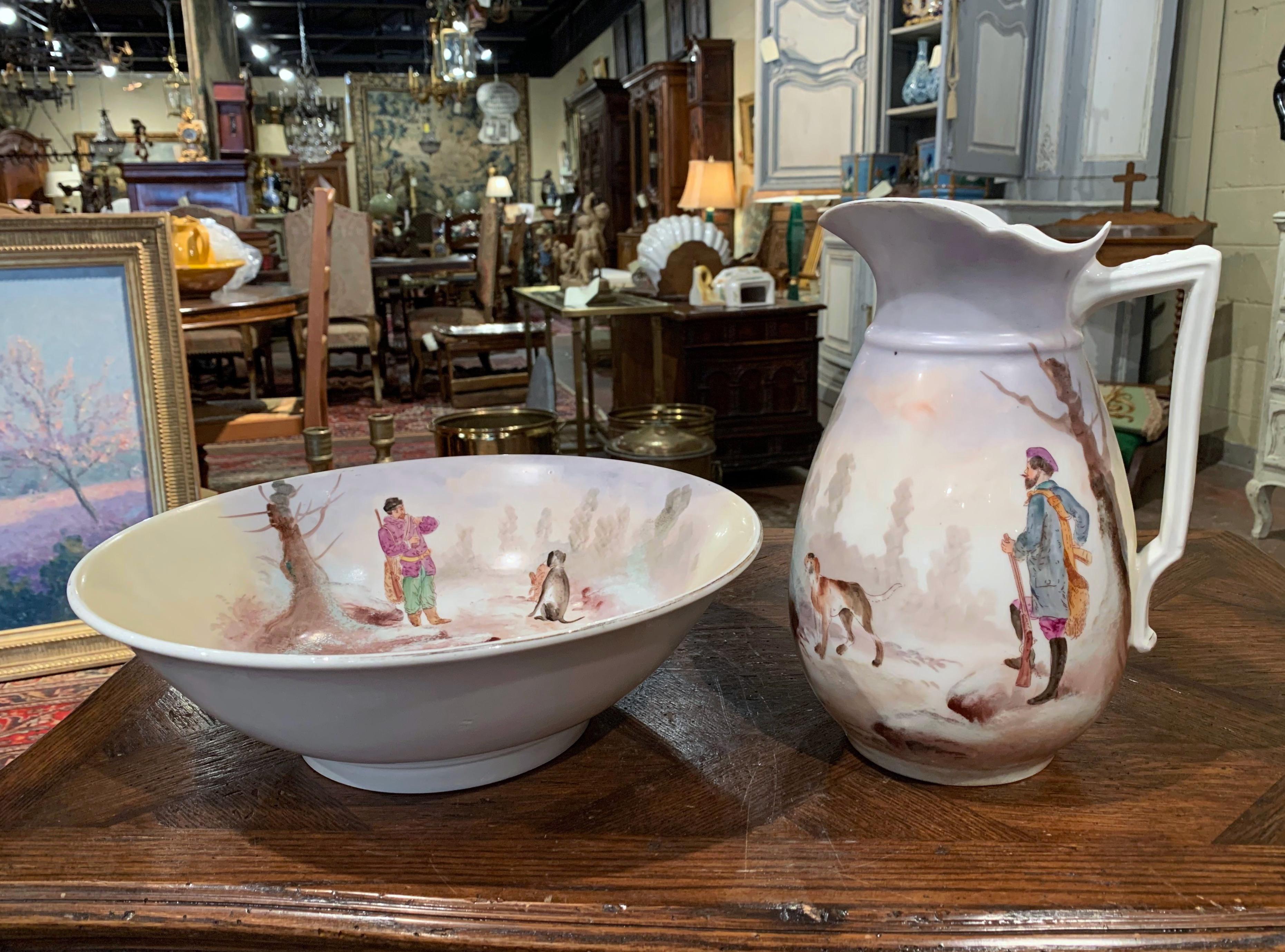 This elegant antique water pitcher with matching bowl were crafted in France, circa 1890; typically used to freshen up in the morning, the ceramic set features a hand painted hunting scene. The basin and pitcher are both depicting a typical hunt
