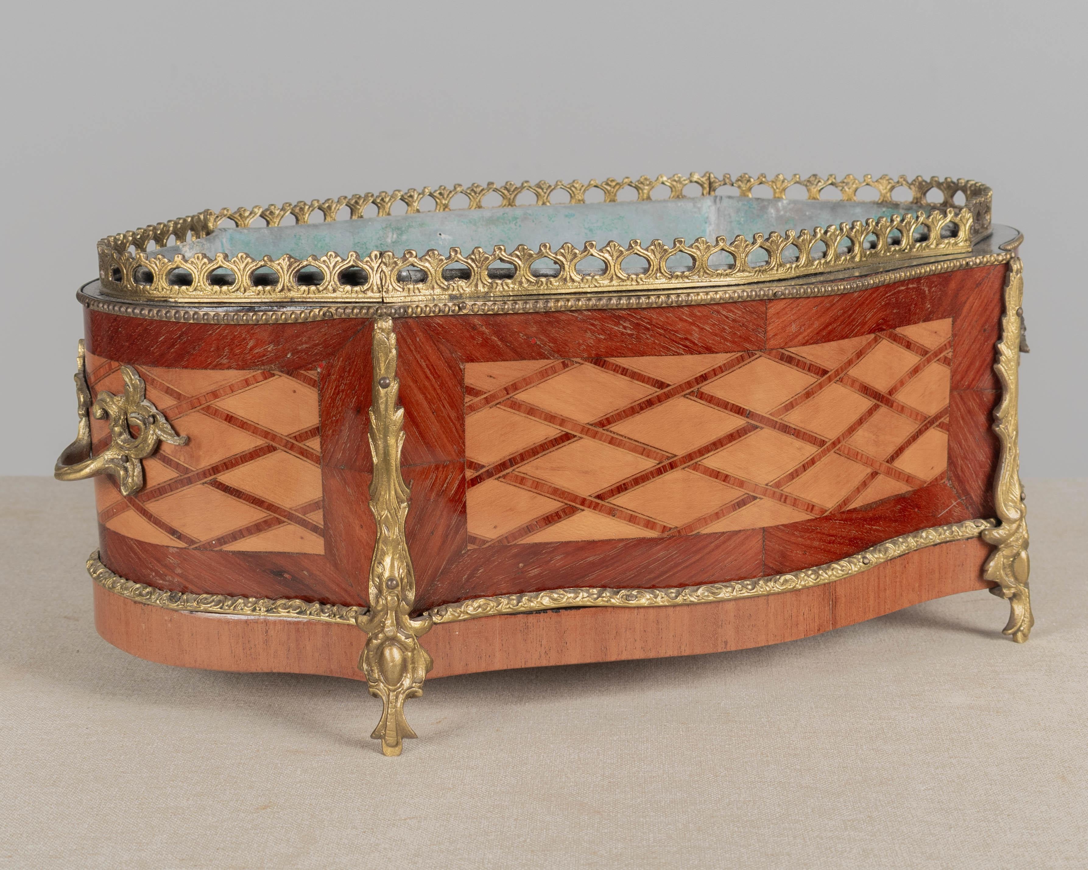 A late 19th century French Napoleon III marquetry jardinière with inlaid veneers of maple and mahogany. Bronze-mounted with two handles, gallery and trim. Original zinc liner may not be water tight. A beautiful planter for the display of orchids.