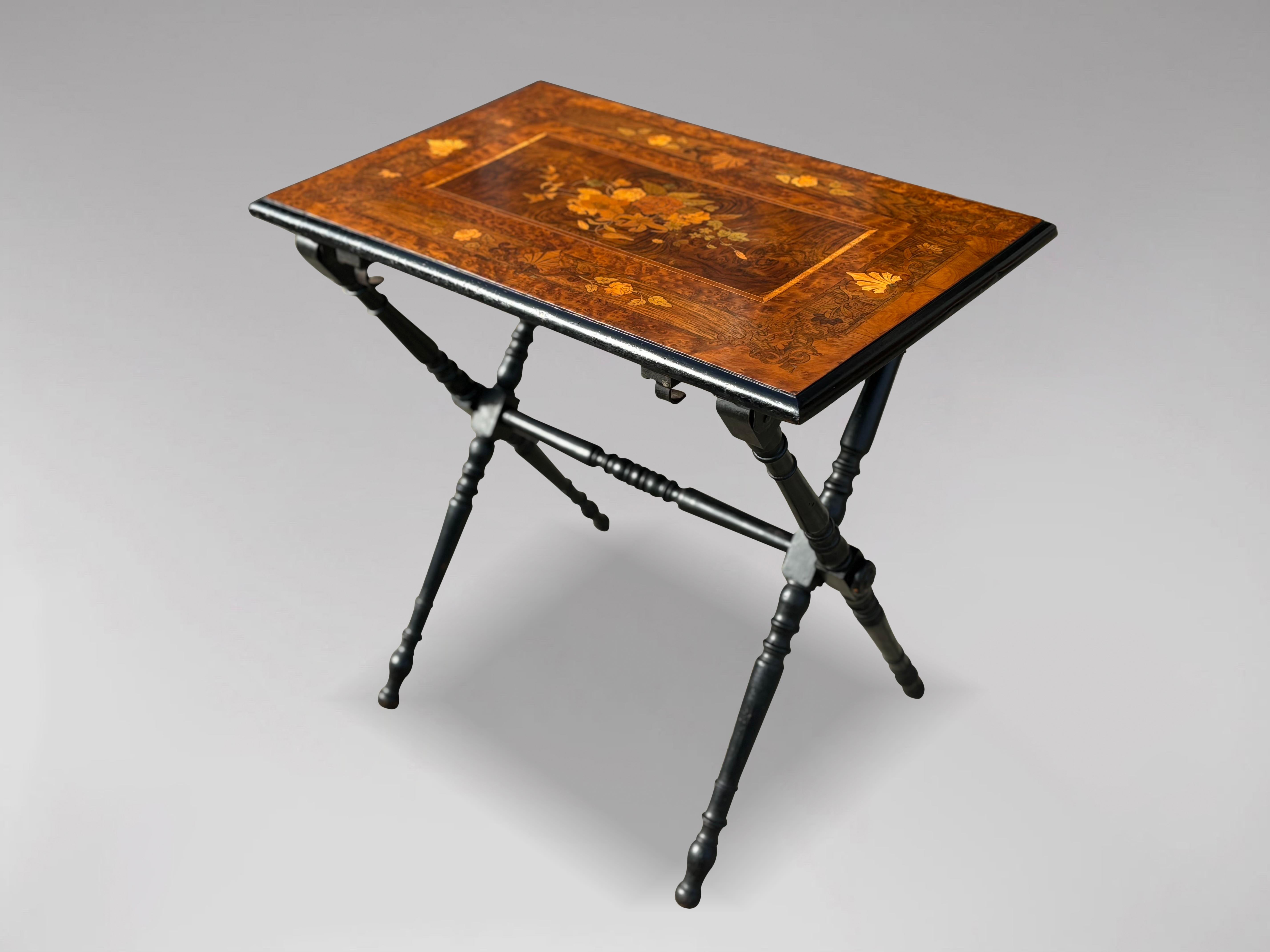 A fine late 19th century French Napoleon III folding table. A rectangular marquetry top made up of several light woods and mahogany inlays, surrounded by a moulded blackened wooden edge. This folding table rests on two pairs of ebonised turned and
