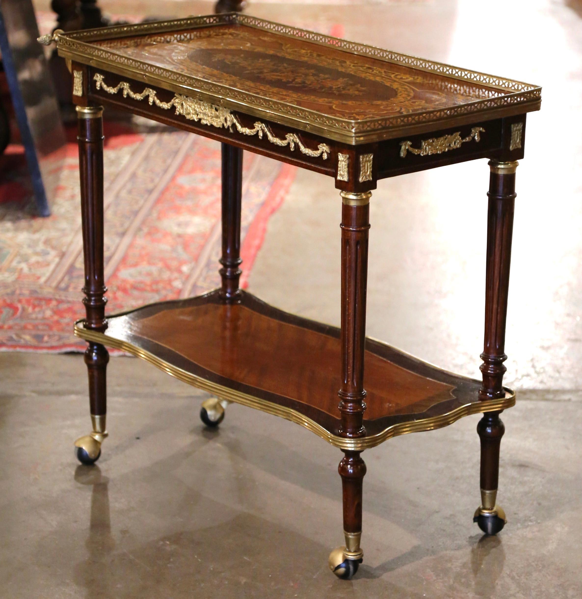 This elegant two-tier wooden and brass cart was created in France, circa 1880. Rectangular in shape, the antique bar cart sits on caster wheels over turned legs, and is dressed with a decorative handle at one end of the top deck. The two plateaus