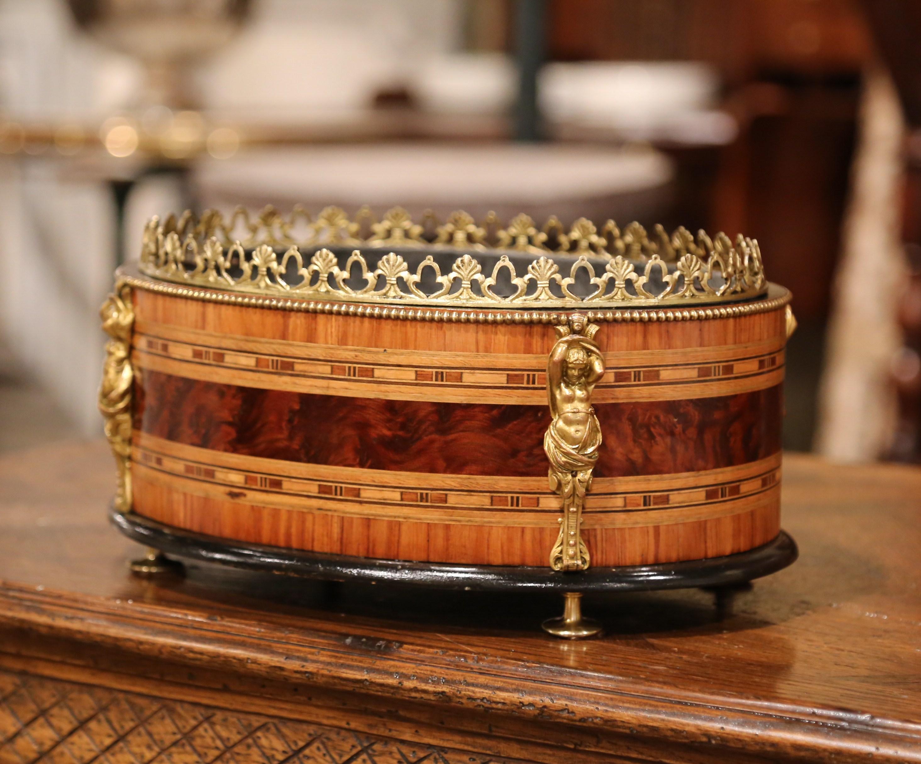 Decorate a dining table or a chest with this elegant, antique oval planter. Crafted in France, circa 1880 the fruit wood jardinière sits on bronze round feet. The jardinière features inlay marquetry geometric decor using different essences of wood