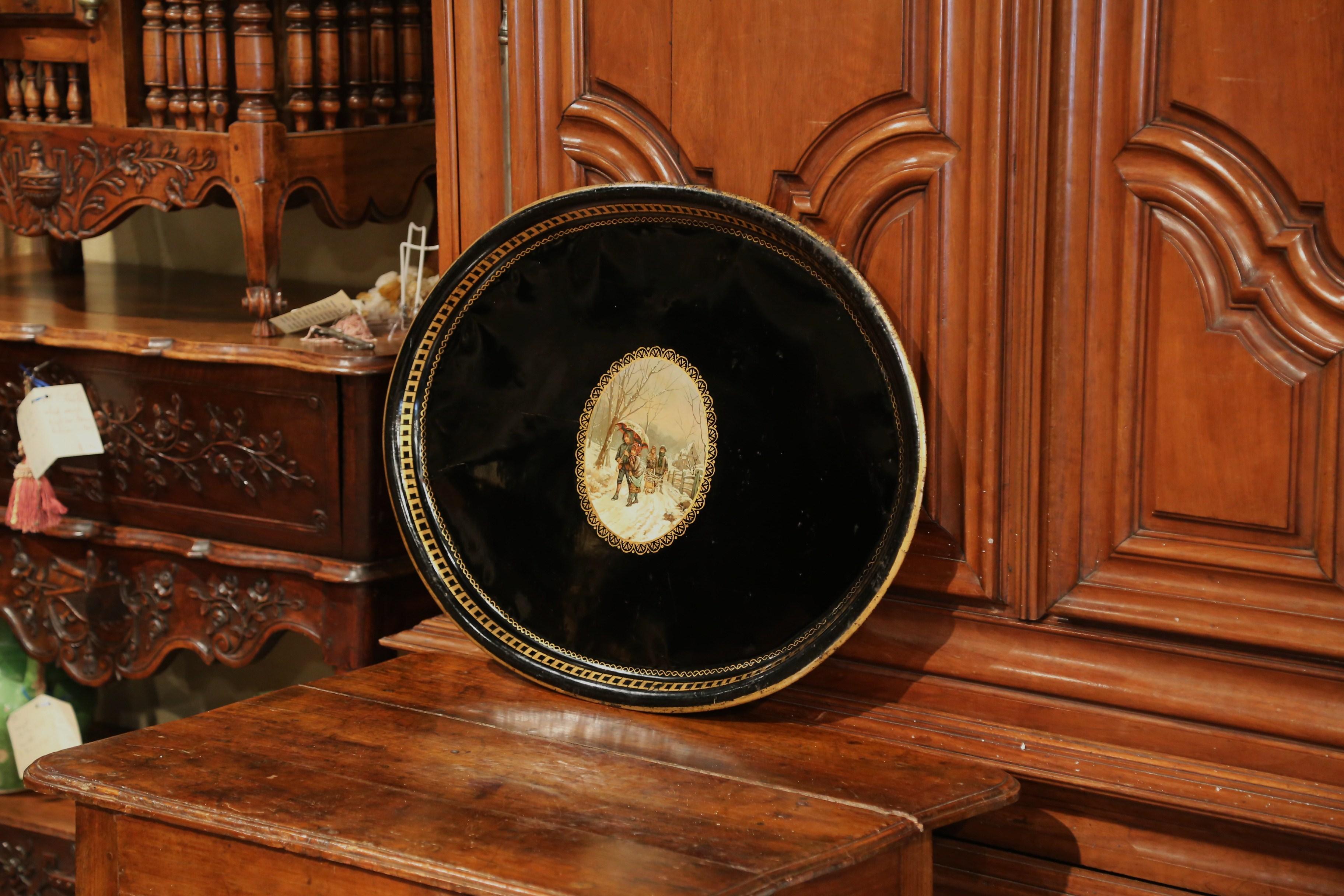 Elegantes antikes Tablett aus Frankreich, um 1870; oval in der Form, ist die große schwarze Tole-Platte durch handgemalten vergoldeten Dekor um die Lippe und eine bunte Winterlandschaft in der Mitte verziert. Die farbenfrohe Szene zeigt junge