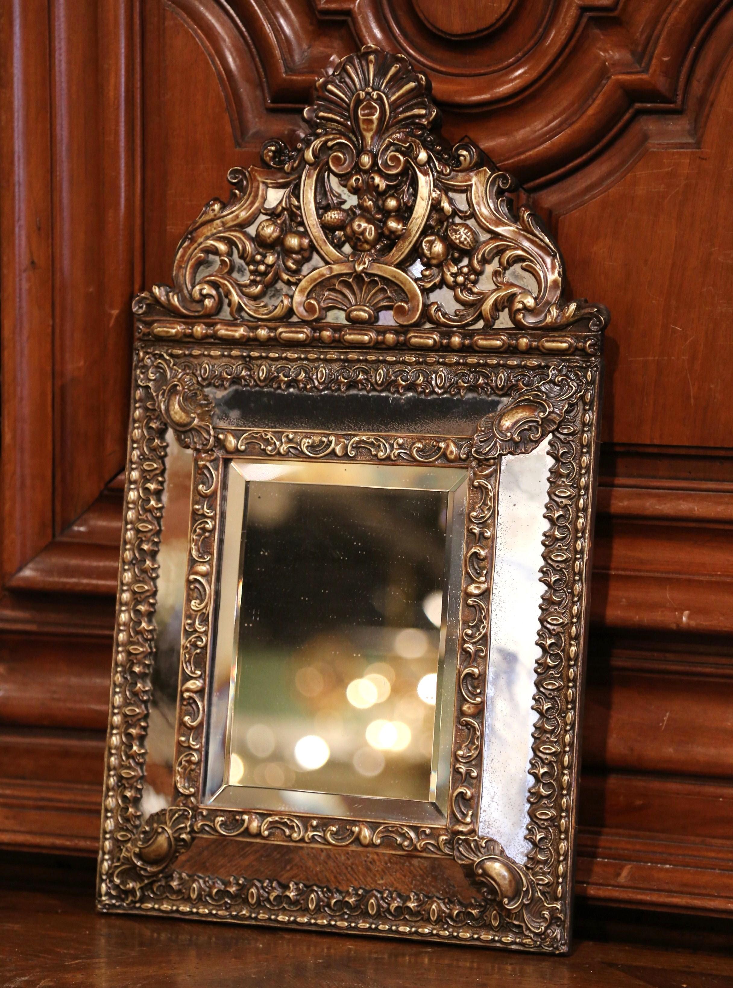 This small, elegant Napoleon III copper mirror was crafted in France, circa 1860. The antique wall hanging repousse piece features an ornate, heavily embellished pediment with a large carved shell and other decorative motifs. The central rectangular