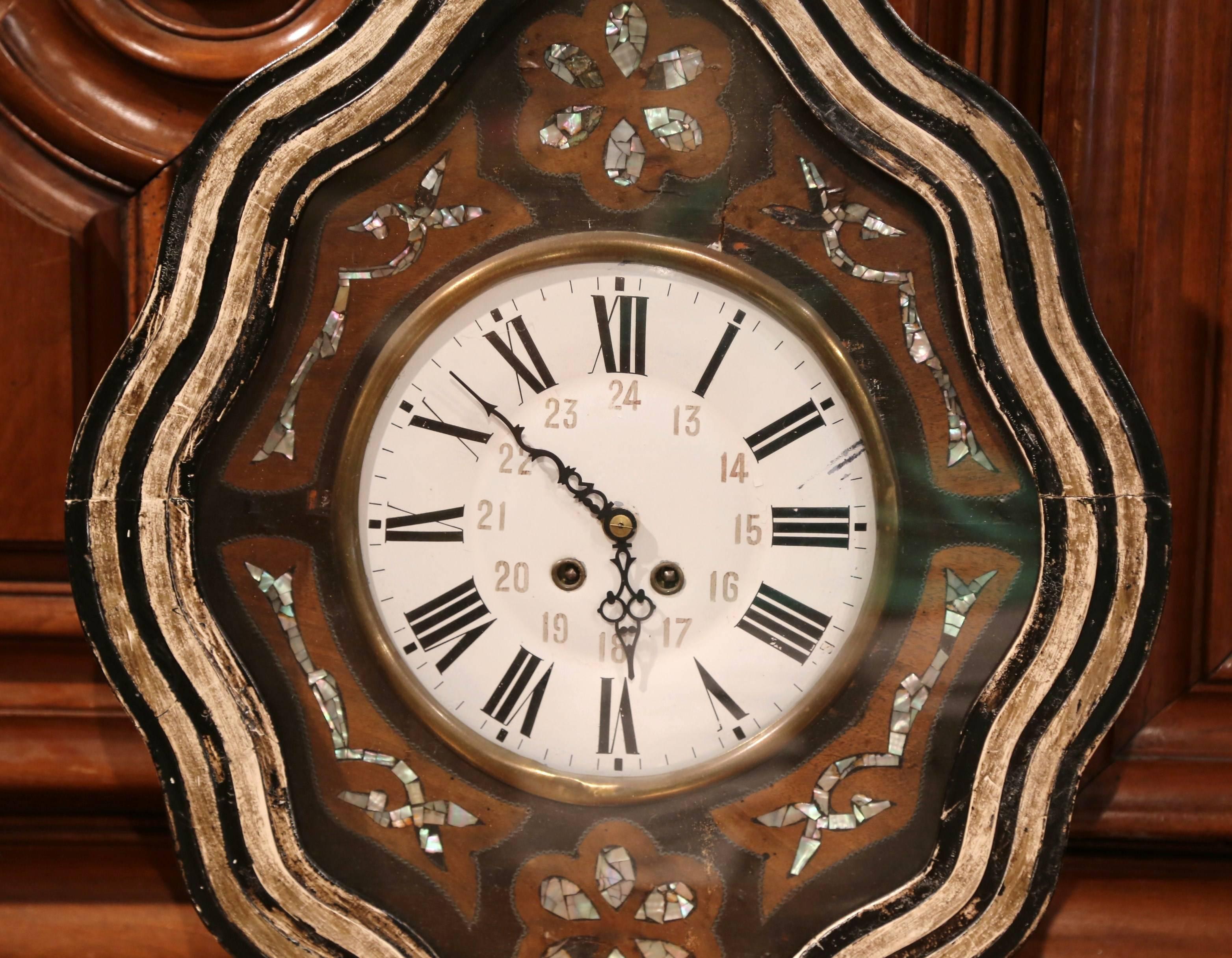 Elegant antique wall hanging clock from France; crafted circa 1870, the oval clock is hand painted around the perimeter; on the facade under the glass top, the piece features mother of pearl decorations. The clock mechanism is good working order and
