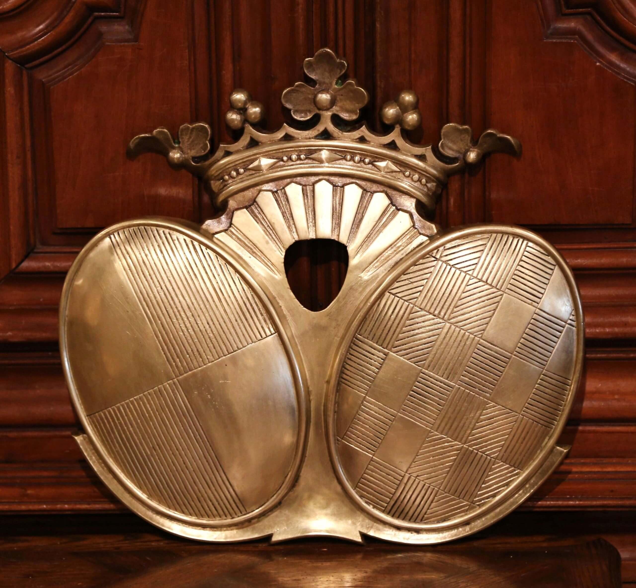 Decorate an office or a study with this elegant antique bronze coat of arms. Crafted in France, circa 1880, the large crest features a crown with leaf and acorn decor, and two oval medallions with checker and stripe motifs. The heavy wall decoration