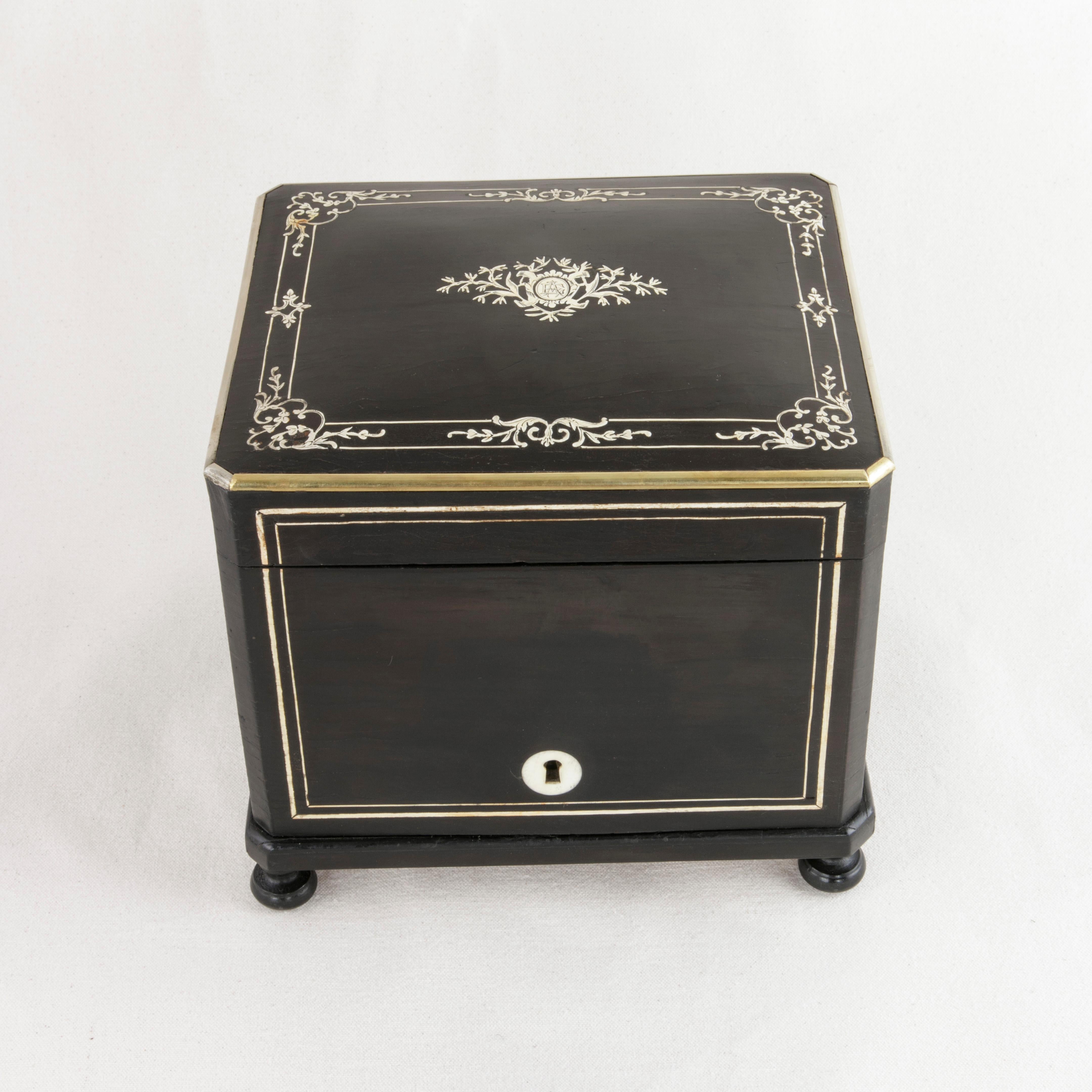 This mid-19th century French Napoleon III period black lacquer Cave a Cigares, or cigar presentation box features a lid of inlaid bone with a central cartouche flanked by leaves and a monogrammed EA. Finely inlaid lines of bone create an inset