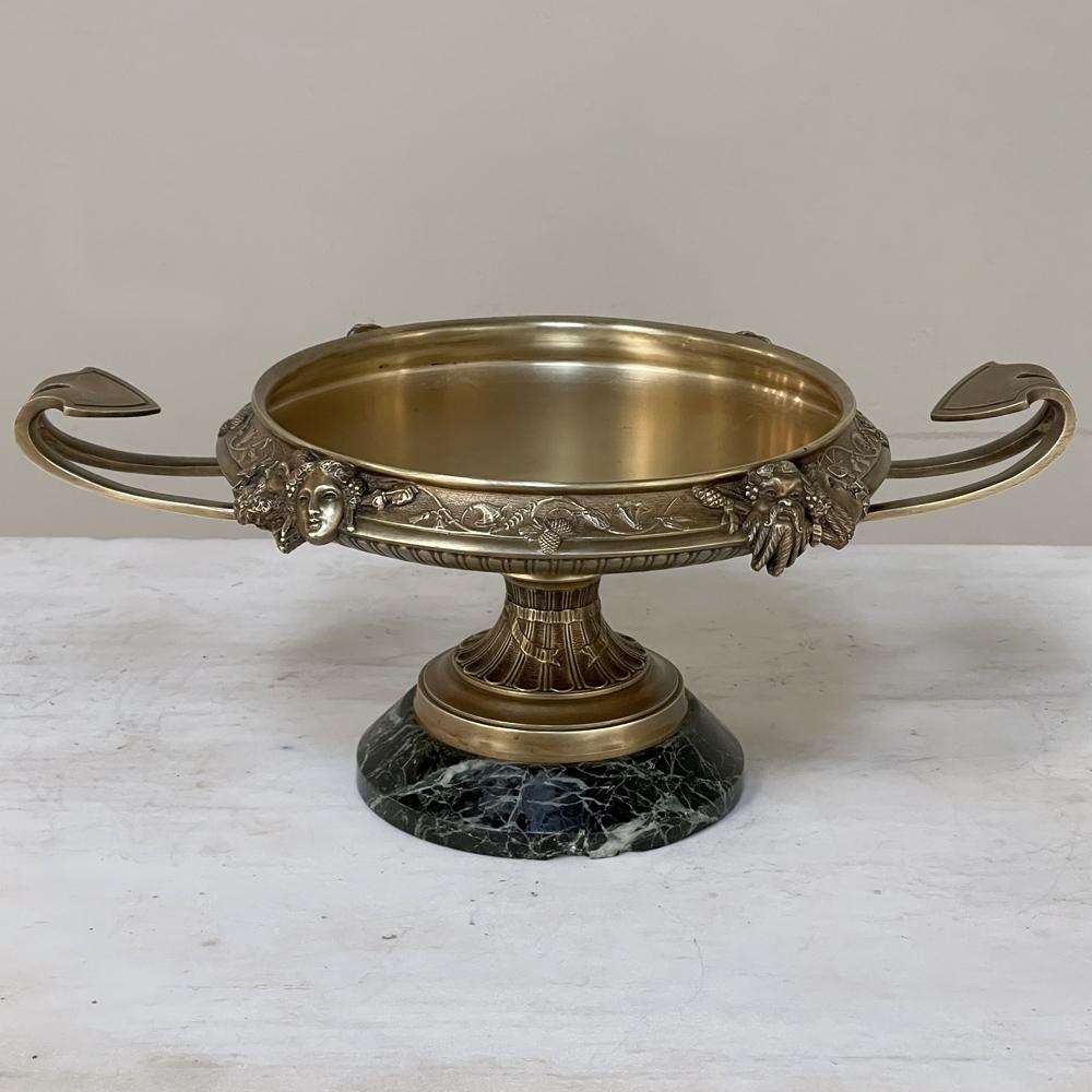 An exceptional 19th century French Napoleon III period bronze centerpiece on marble base depicts Bacchus and Ariadne in full relief, plus an intriguing dragon's tail handle on each side for symmetry. The bowl rests atop a neoclassical pedestal,