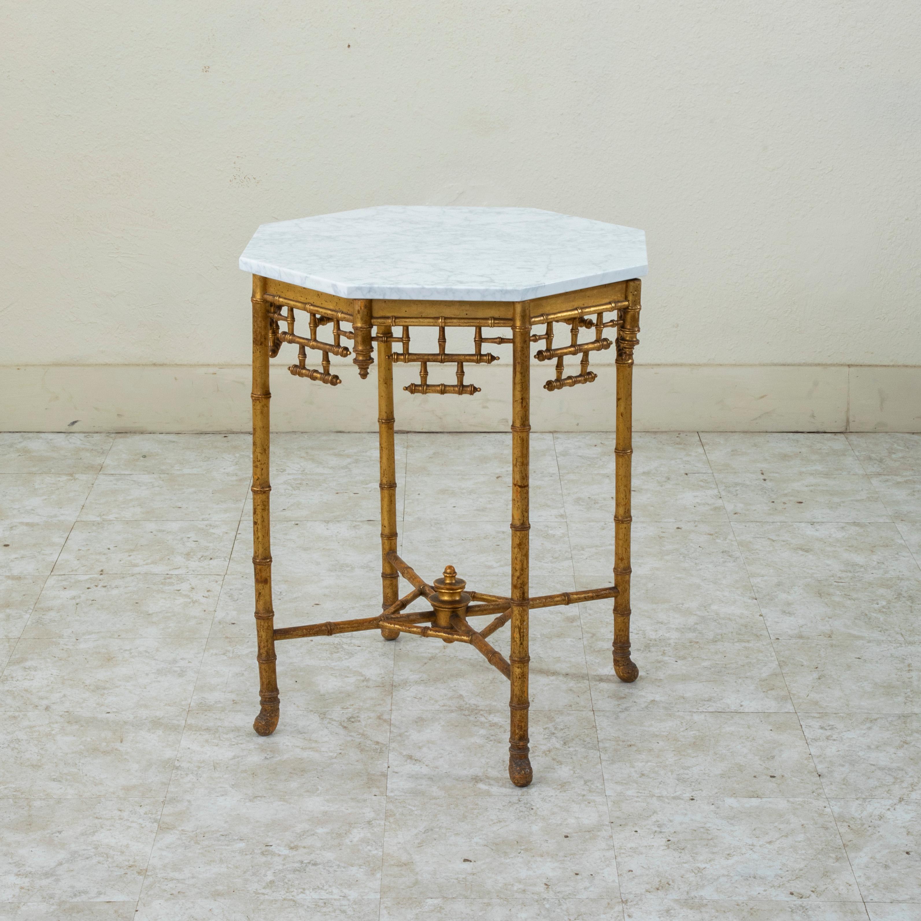 Cette table d'appoint en faux bambou doré d'époque Napoléon III du milieu du XIXe siècle présente un plateau octogonal en marbre blanc. Le tablier est orné d'un motif en treillis de bambou. Les quatre pieds sont reliés par un châssis inférieur en X