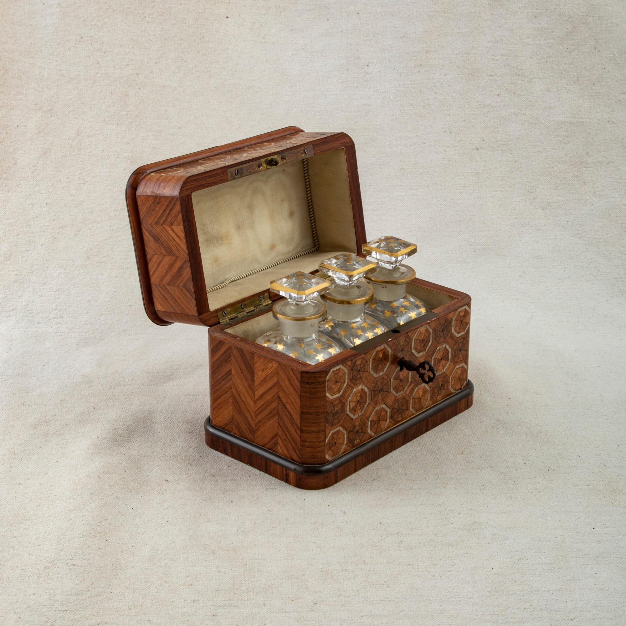 This mid-nineteenth century French Napoleon III period rosewood marquetry perfumer's box features mother-of-pearl inlay that creates a geometric octagonal pattern on the top and front. The sides of the box are detailed with a chevron pattern in