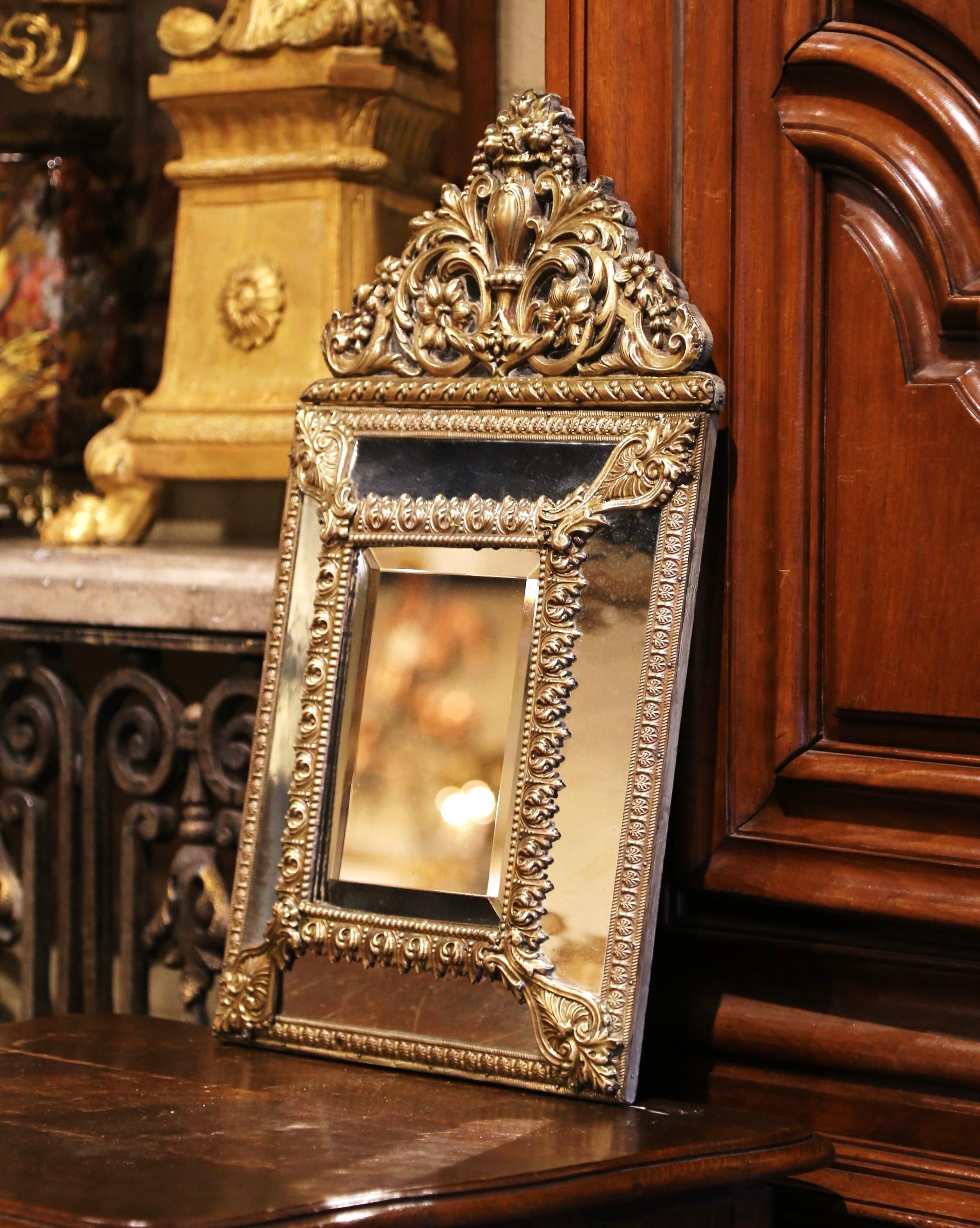Créé en France vers 1870, cet élégant miroir ancien est décoré de motifs complexes de rinceaux repoussés, dont un grand cartouche au fronton présentant une corbeille de fruits au centre, flanquée de rinceaux et de feuillages de part et d'autre. Le