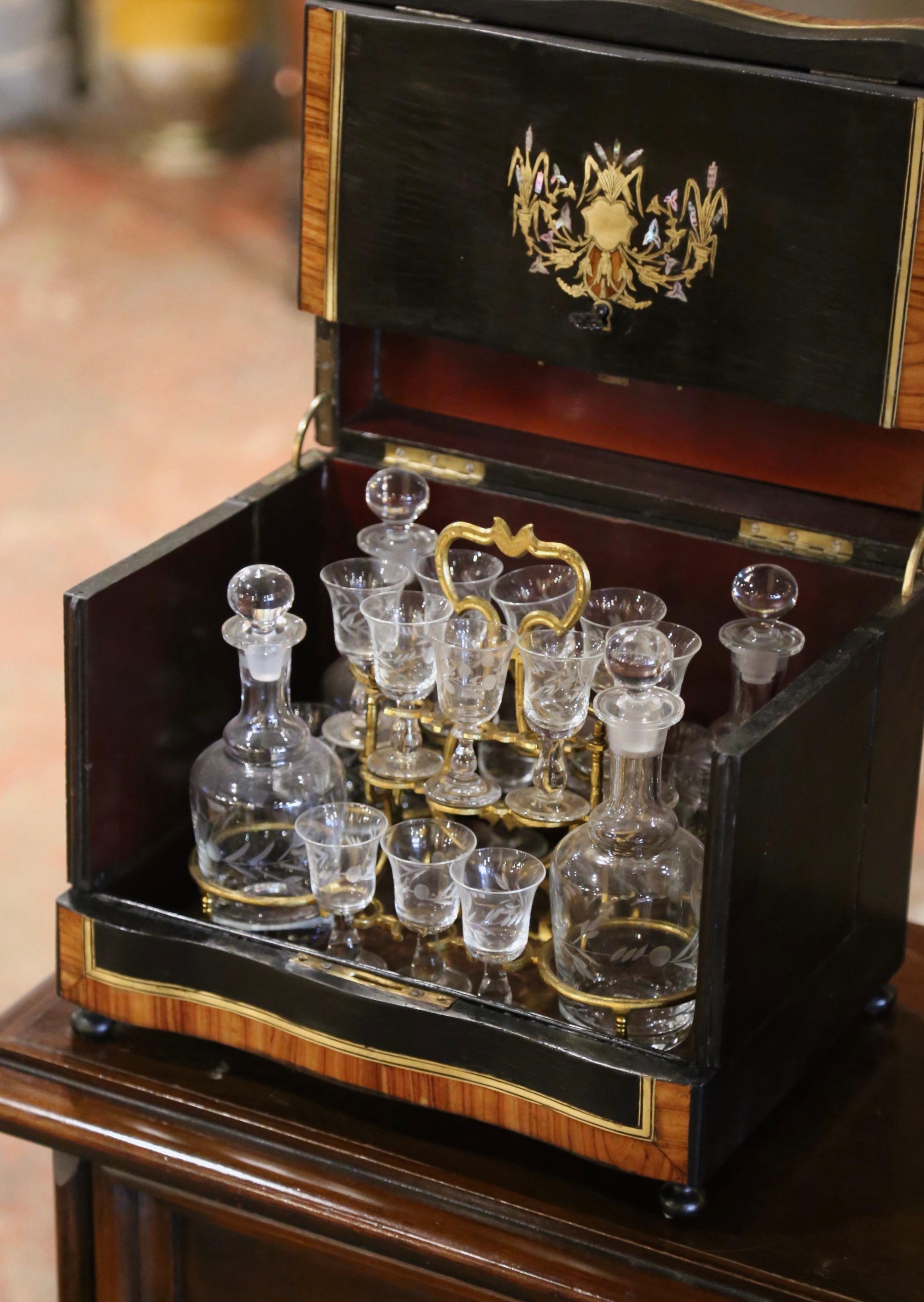 Create an elegant bar area with this complete antique liquor box. Created in France circa 1870, and rectangular in shape with serpentine front, the Tantalus stands on small round feet. The box is decorated with marquetry and brass inlaid medallions