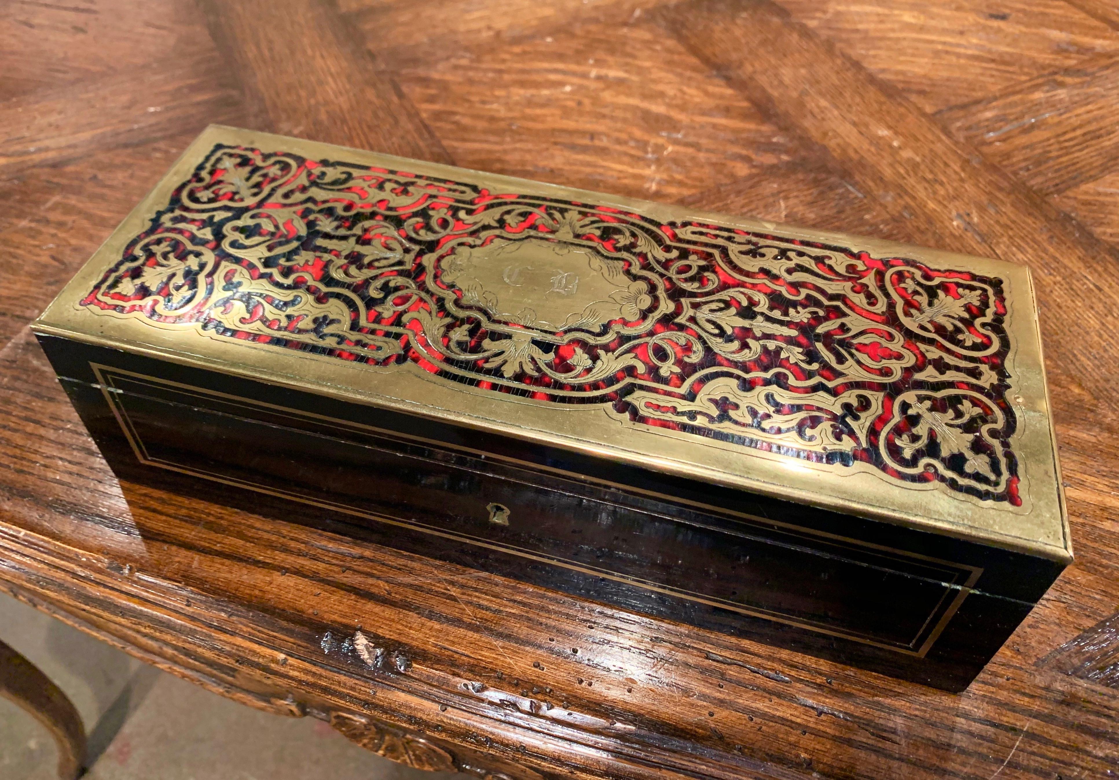 Created in France circa 1880 in the manner of André-Charles Boulle, the rectangular box with drop-down front, is decorated with arabesques of gilded brass inlay motifs on the top with the initials 