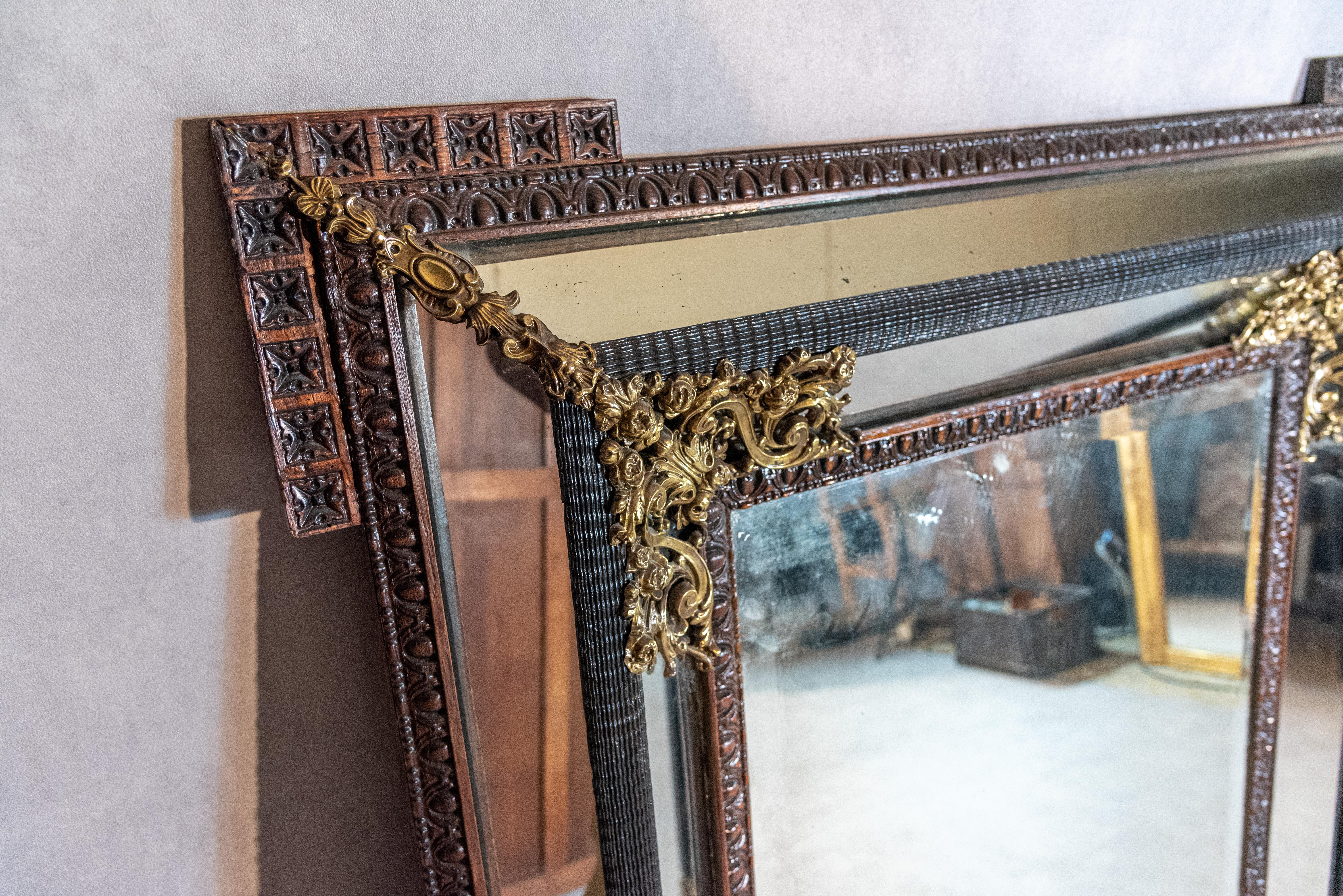 A unique 19th century French Napoleon III style parecloses mirror with beautiful proportions and a unique frame design. This authentic mirror features wonderful brass ornamentations and finishes, stunning wood carvings, and a mirror glass in fine