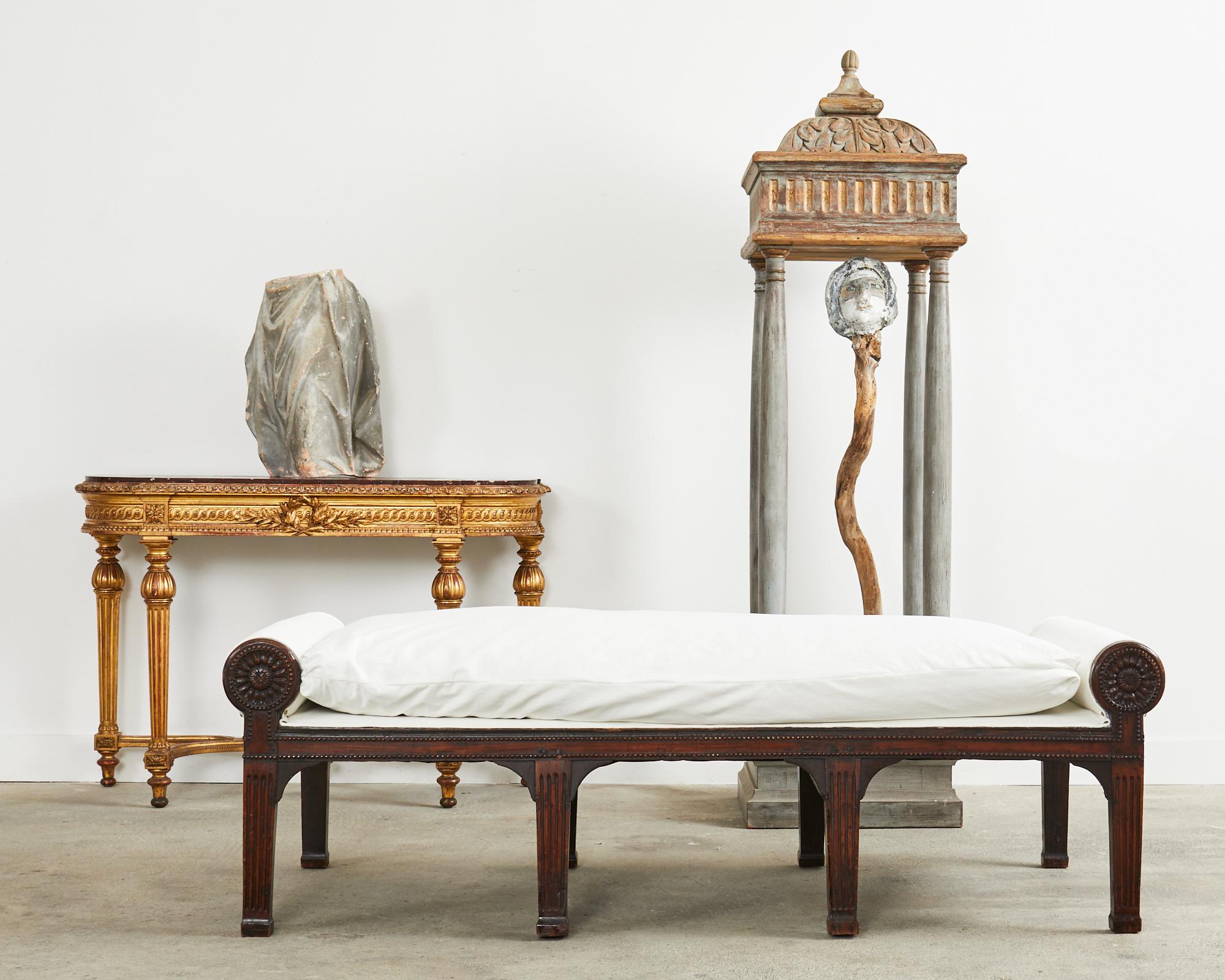 Distinctive 19th century walnut daybed or bench seat made in the grand French Napoleon III period. The walnut frame features large round padded bolsters on each end decorated with stylized floral motifs. Supported by eight neoclassical fluted column
