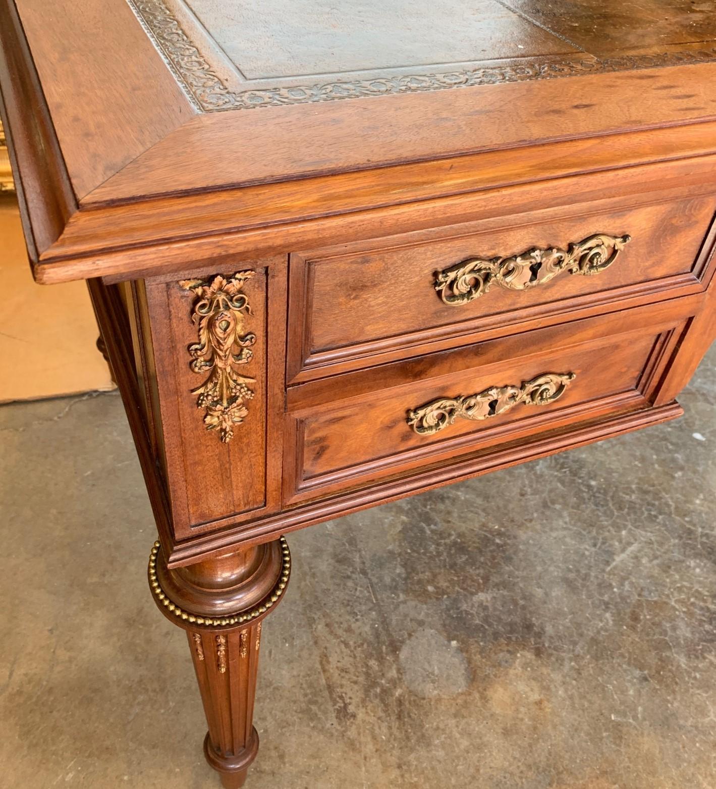 Handsome 19th century French Napoleon III writing table or desk crafted of fine plum mahogany and having a tooled leather top. Superbly appointed with grape cluster and leaf cast bronze appliques, and foliate inspired bronze escutcheons. The entire