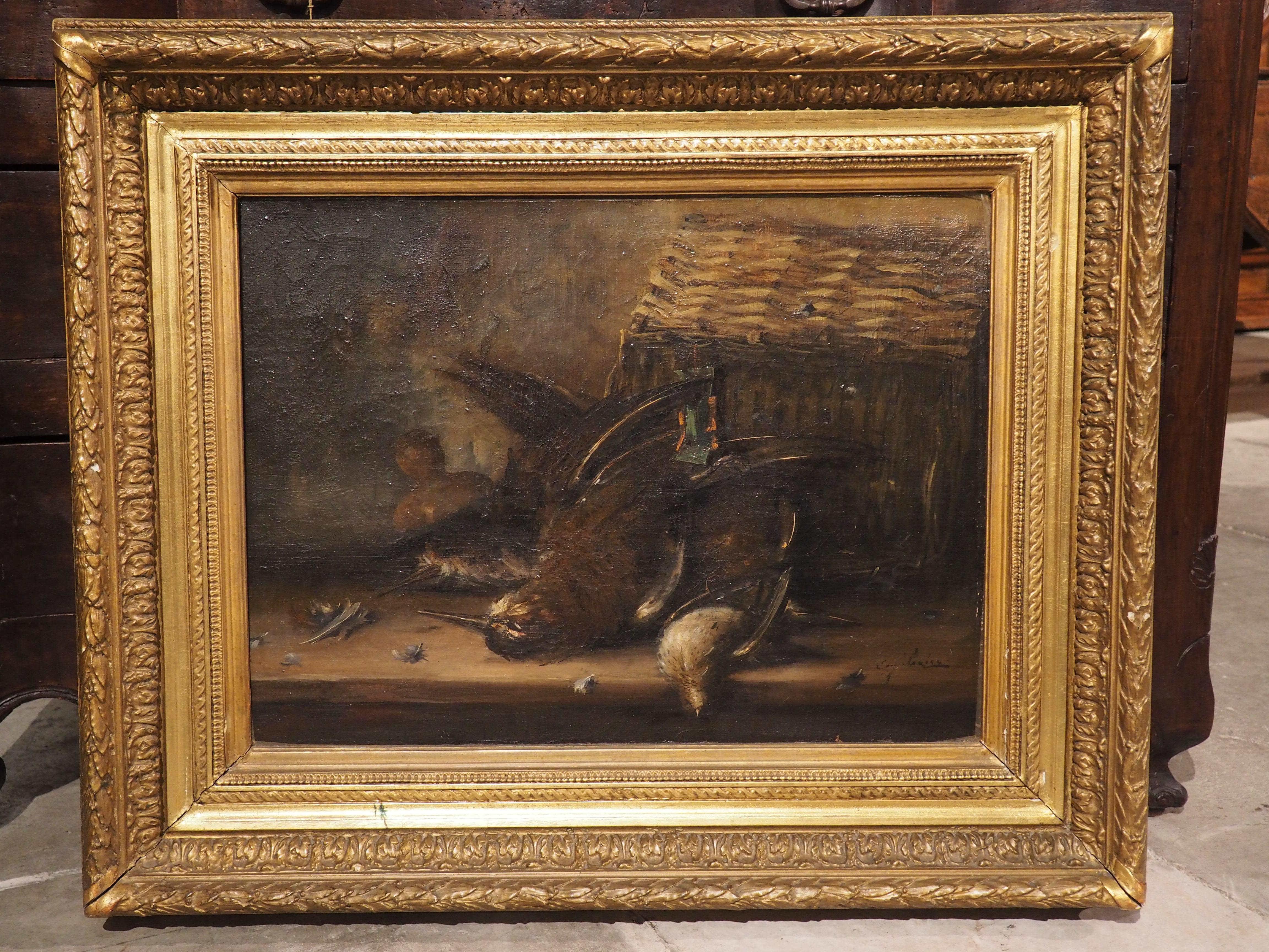 Signed in the lower right hand corner by the artist, this French nature morte (still life) painting is surrounded by a giltwood frame embellished with foliage, Vitruvian waves, and spiral fluting. The subject of the oil on canvas painting is a trio