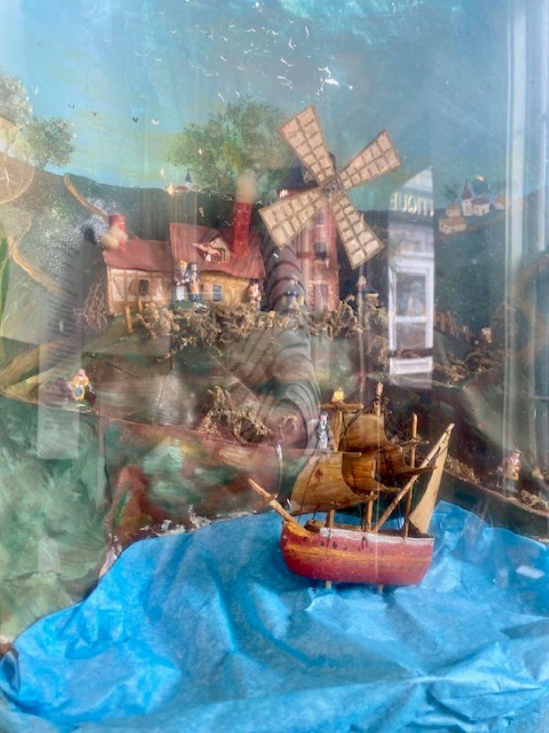 Antico automa nautico francese, probabilmente di Marsiglia, del 1860 circa, un diorama a cupola in vetro con mulini a vento e casette sul fianco di una collina, che si affaccia sul porto con una nave che dondola sulle onde con un motivo musicale.