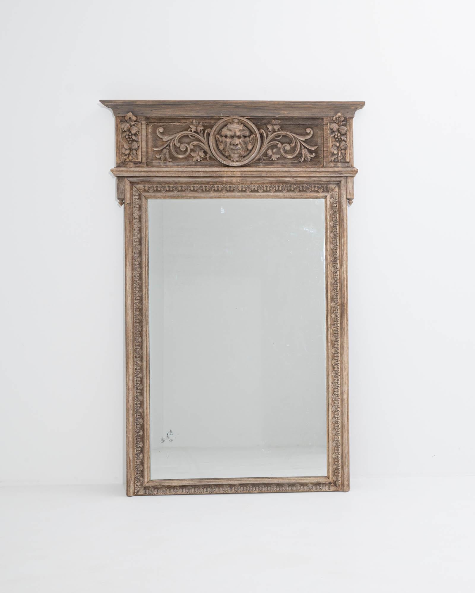 Stately yet vivacious, this antique mirror in natural oak is a masterly work of craftsmanship. Made in France in the 1800s, the design evokes the ornate aesthetics of Renaissance villas and palaces. The architectural proportions of the frame creates
