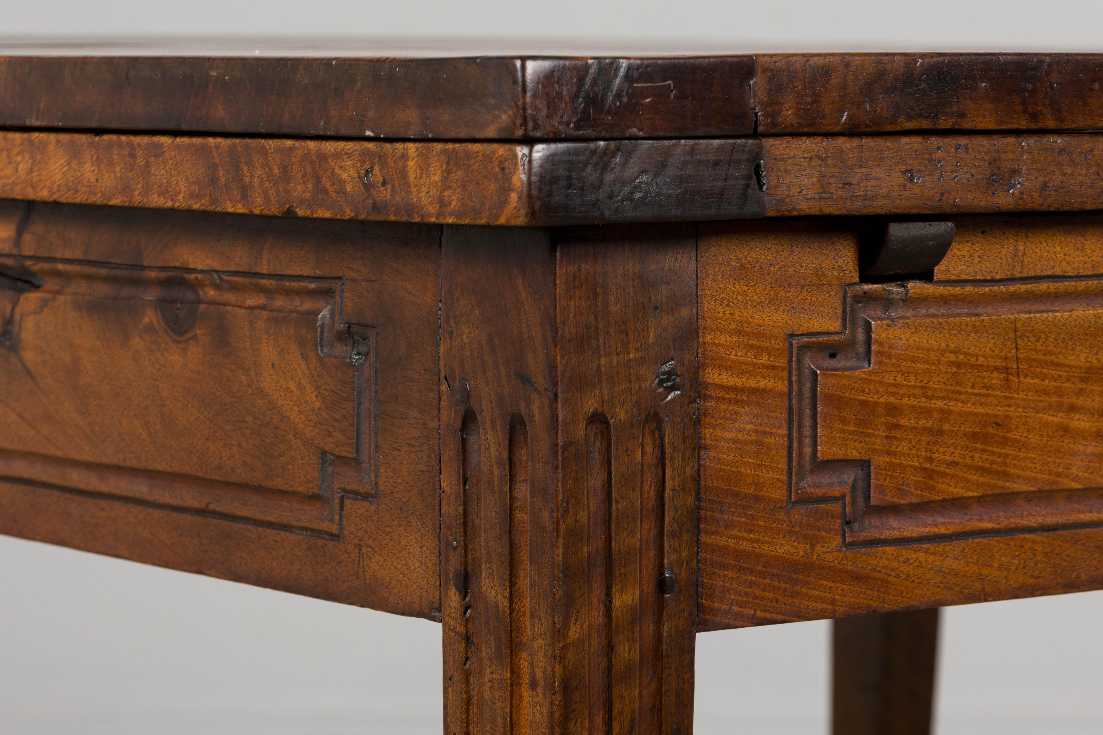A charming mid-19th century French extendable dining table in Louis XVI style, sourced from Provence, France. Beautifully hand-crafted from solid walnut, the table showcases a deep, naturally aged patina with expressive grain movement and