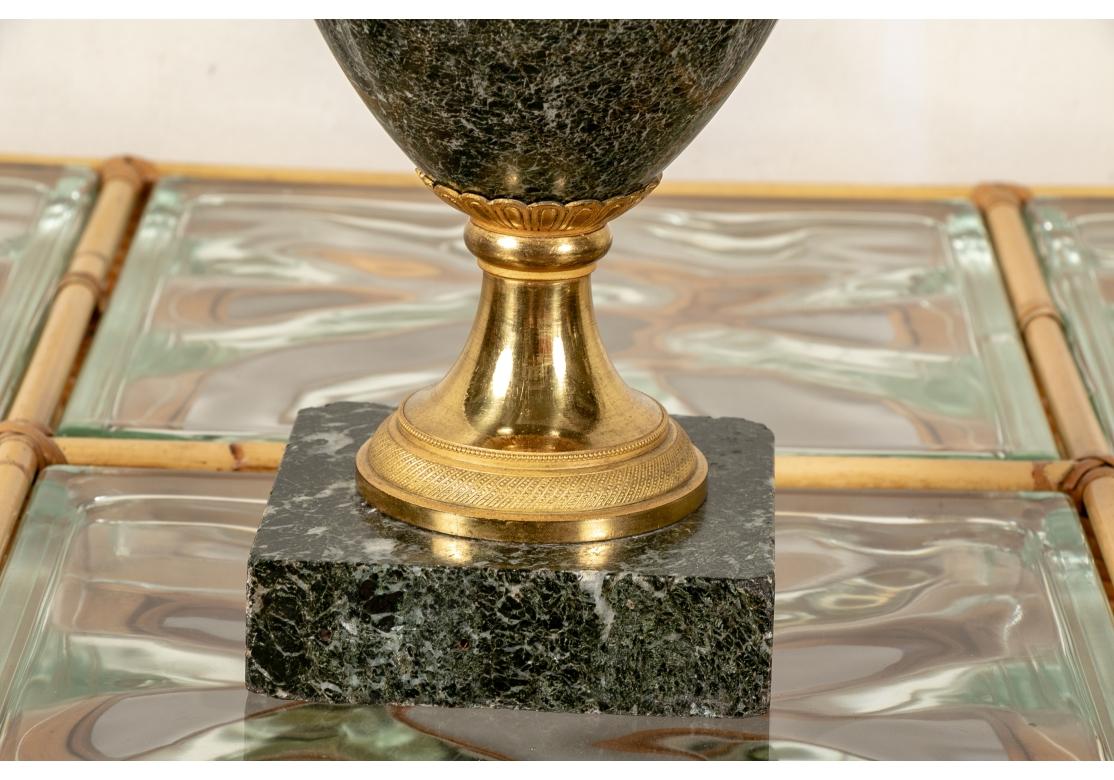 Une belle urne cassolette française en marbre vert avec des montures néoclassiques en bronze doré brillant. Le bord est orné d'une bande de feuilles et de rubans et les deux anses droites sont décorées de rosettes et de feuilles en relief et se