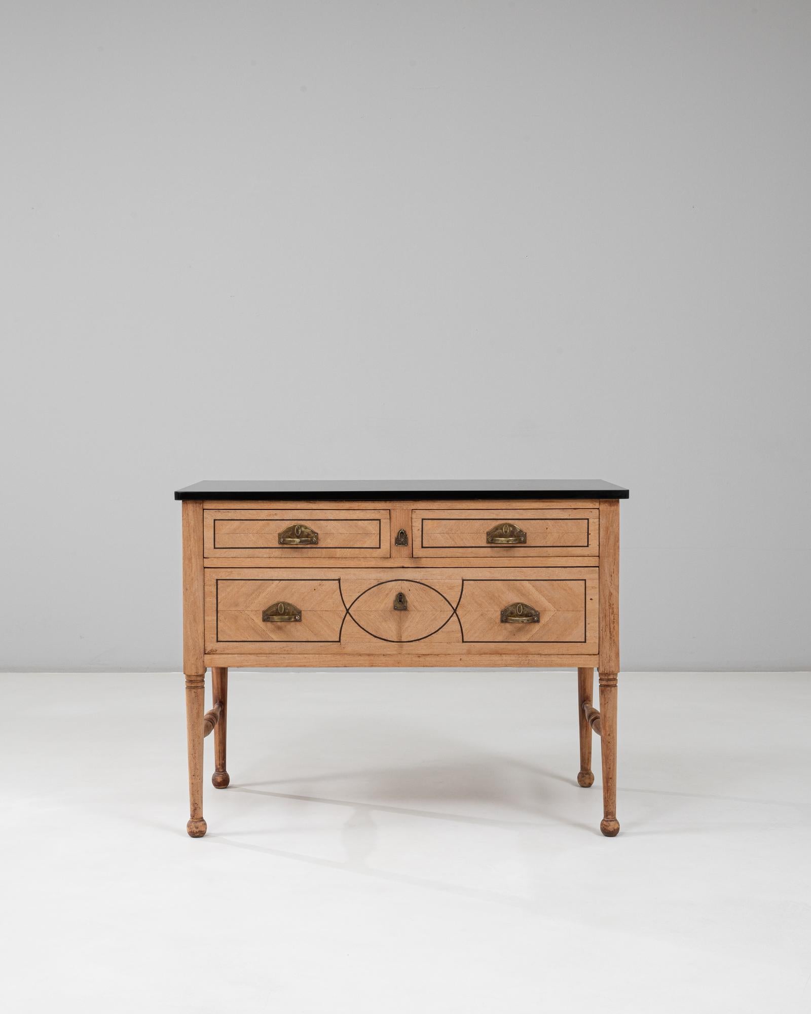 Questa cassettiera neoclassica francese del XIX secolo con piano in marmo presenta un raffinato equilibrio di simmetria, proporzioni e dettagli architettonici. Il legno chiaro è accentuato da precisi intarsi neri che formano motivi geometrici e un