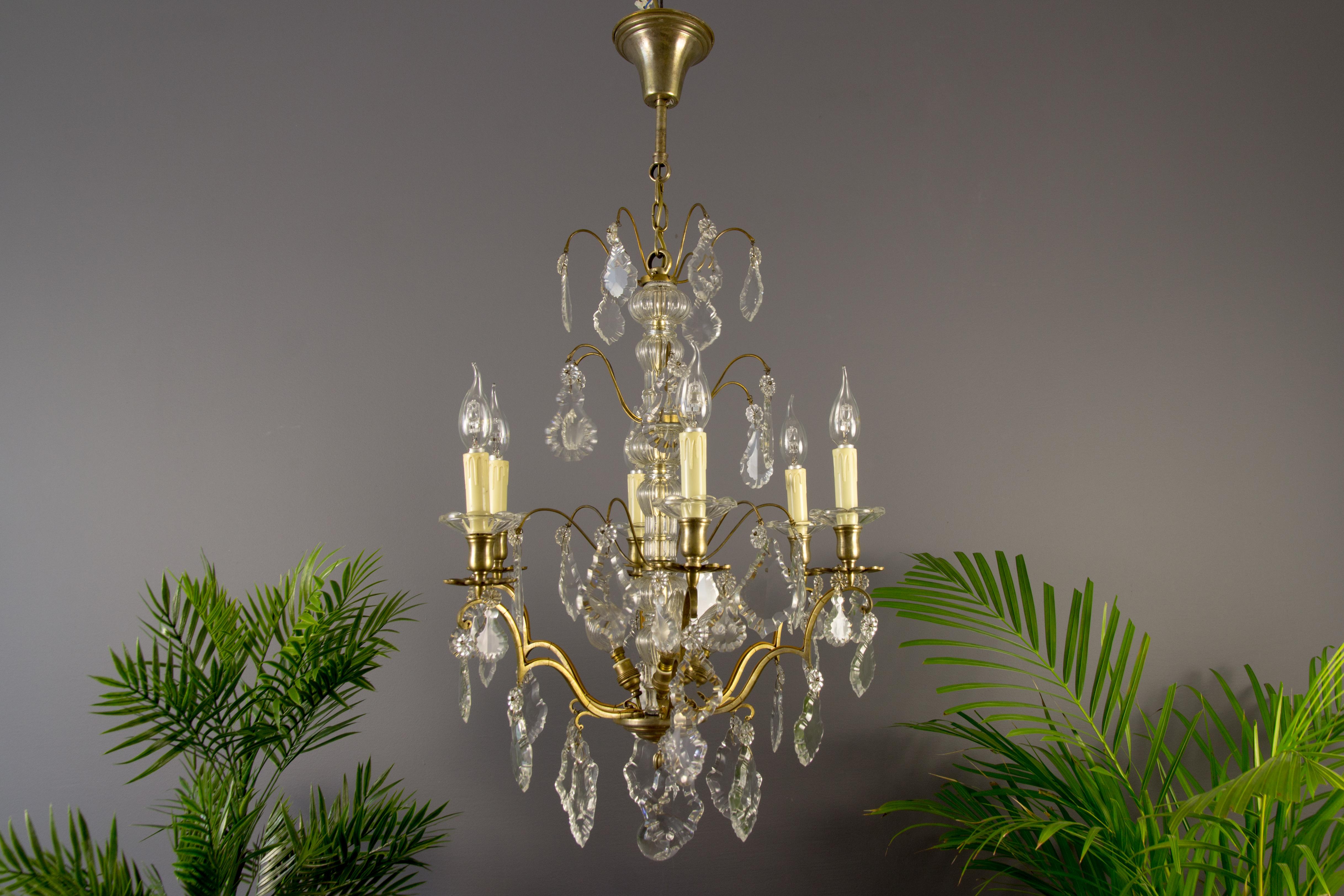 A stunning crystal and brass chandelier made in France in circa 1880. Originally crafted for 6 candles, this antique chandelier has been electrified and is newly rewired. Six brass arms with flower shaped brass and crystal bobeches, each with socket