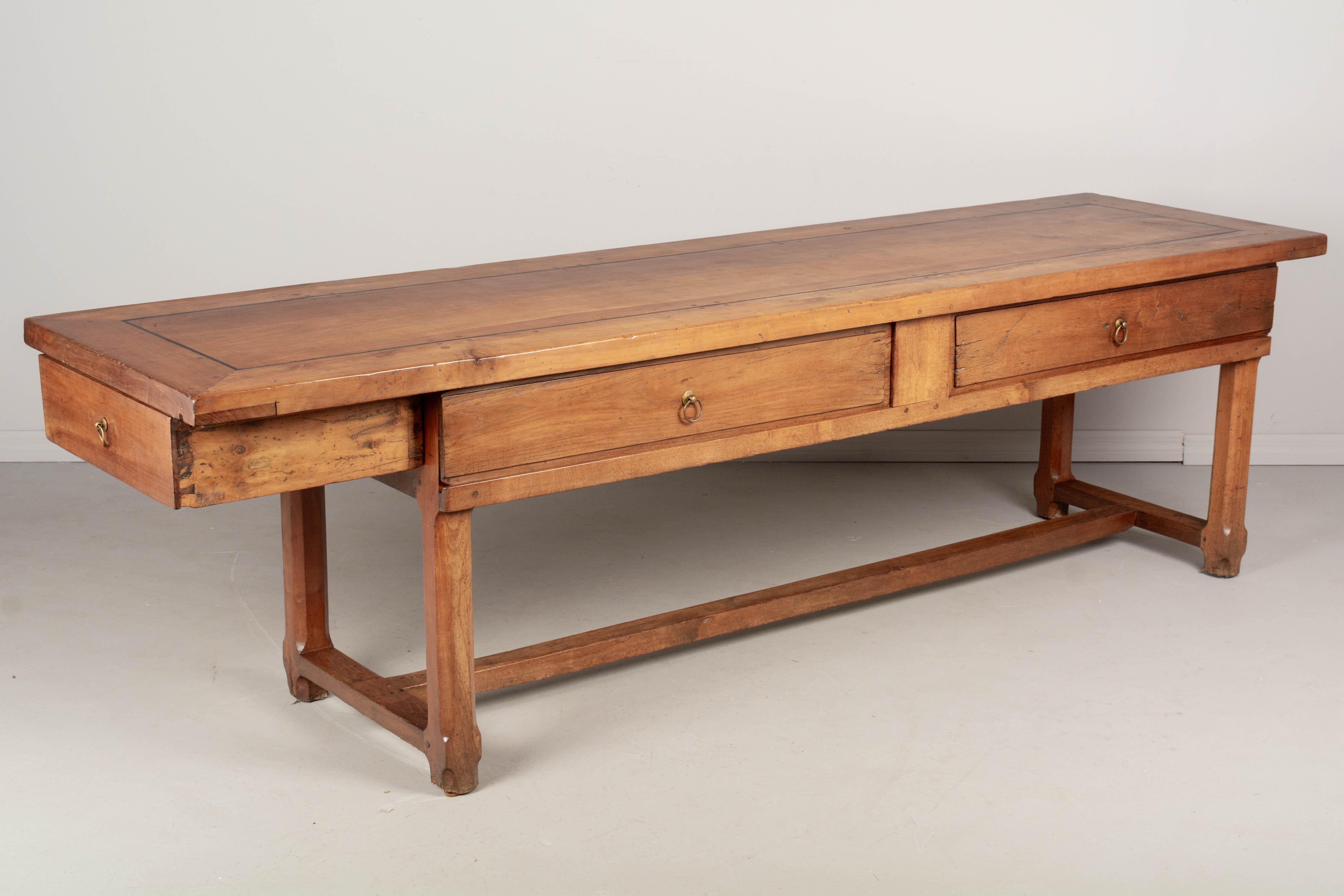 A 19th Century French Country farm table or work table from Normandy. Made of solid cherry wood with two sliding doors along the front and one deep dovetailed drawer at the end, each with brass ring pulls. The top is made from a 2