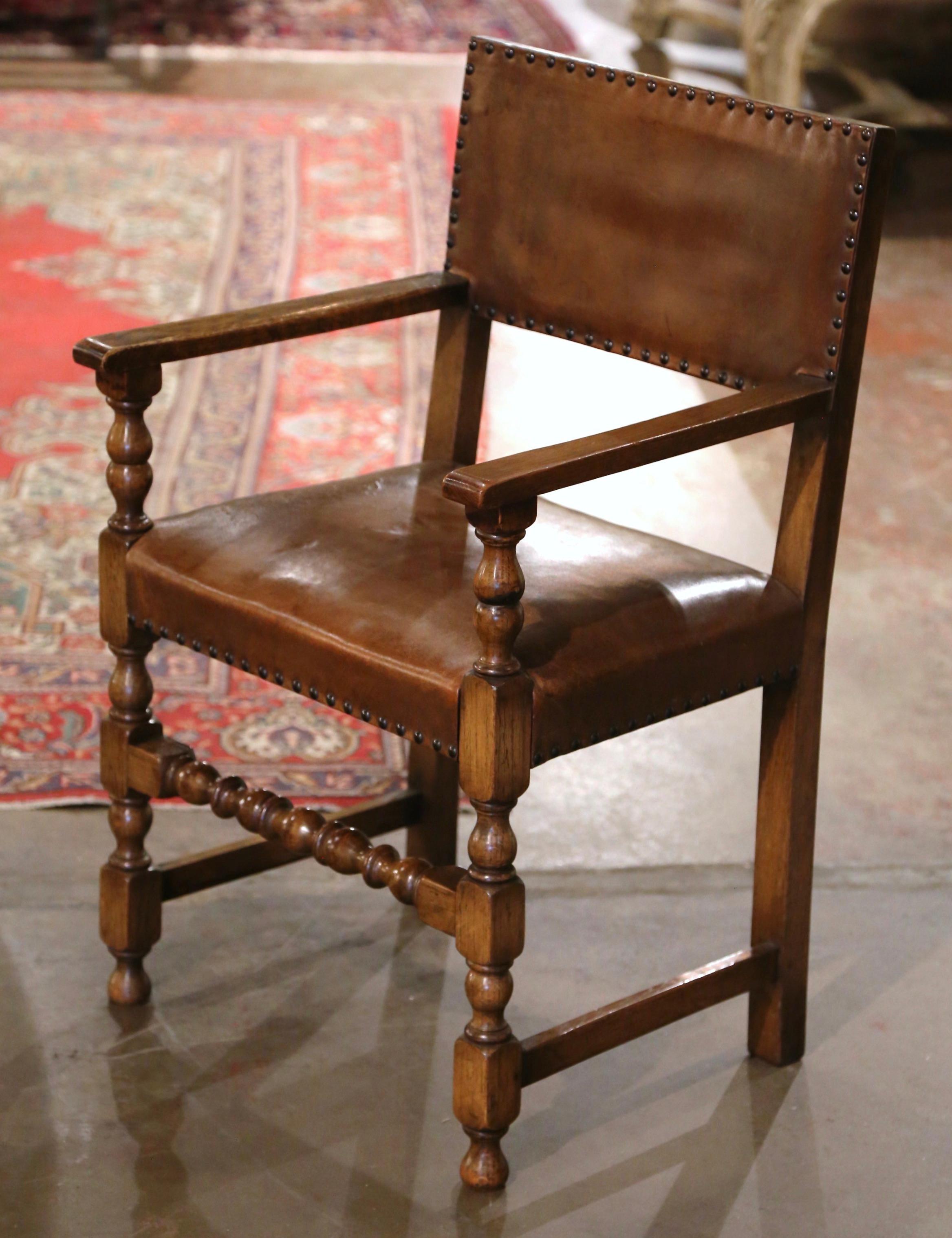 Crafted in Southern France circa 1890, and built of oak wood, the comfortable armchair stands on front turned legs with bottom stretcher; it features a wide seat, open armrests and a curved rectangular back. The chair is upholstered with the
