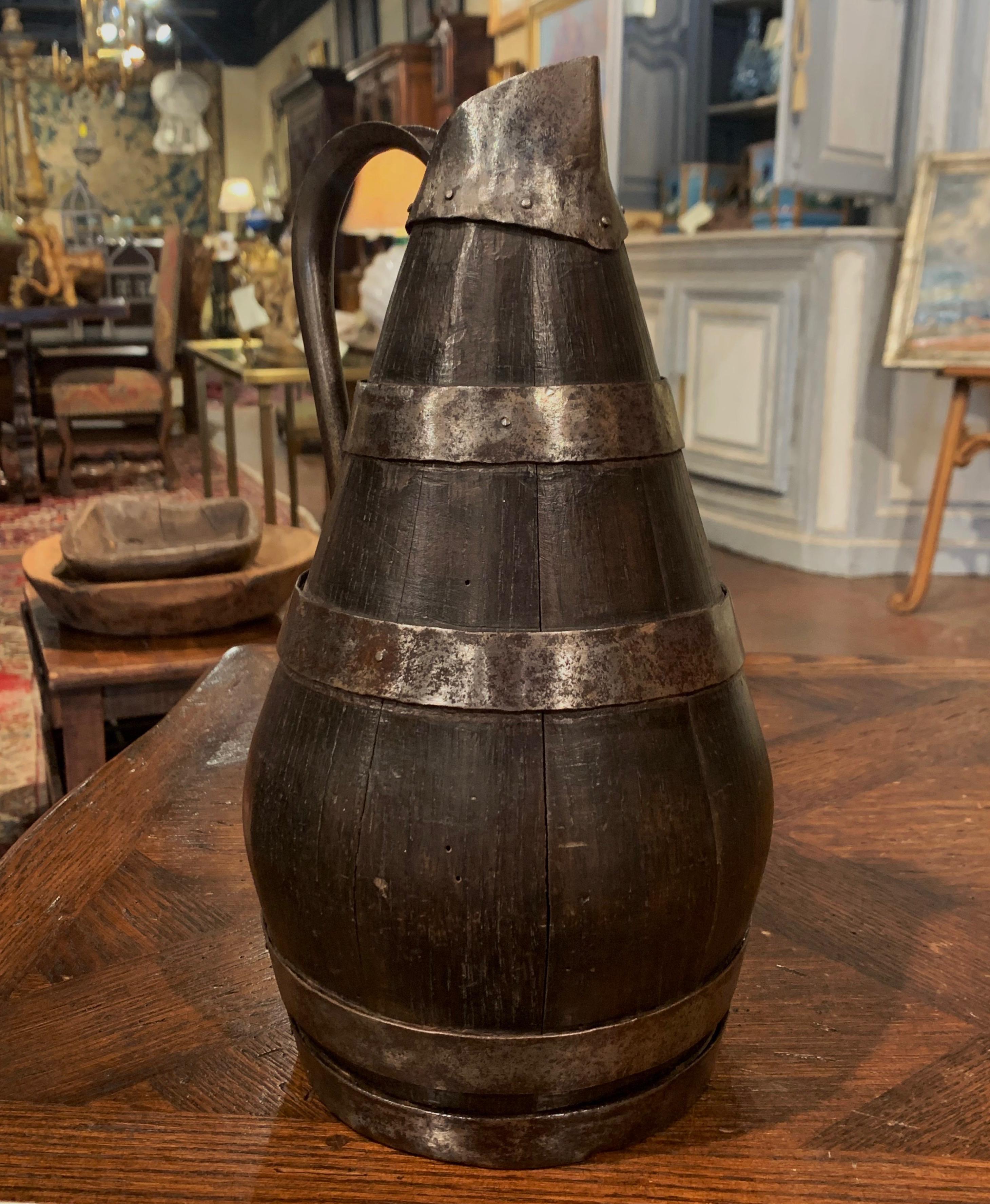 Accessorize your wine cellar or wet bar with this antique cider pitcher; crafted in Normandy France circa 1870, the pitcher is made of barrel oak decorated with polished metal rings. The cider pitcher, further embellished with a metal handle, is in
