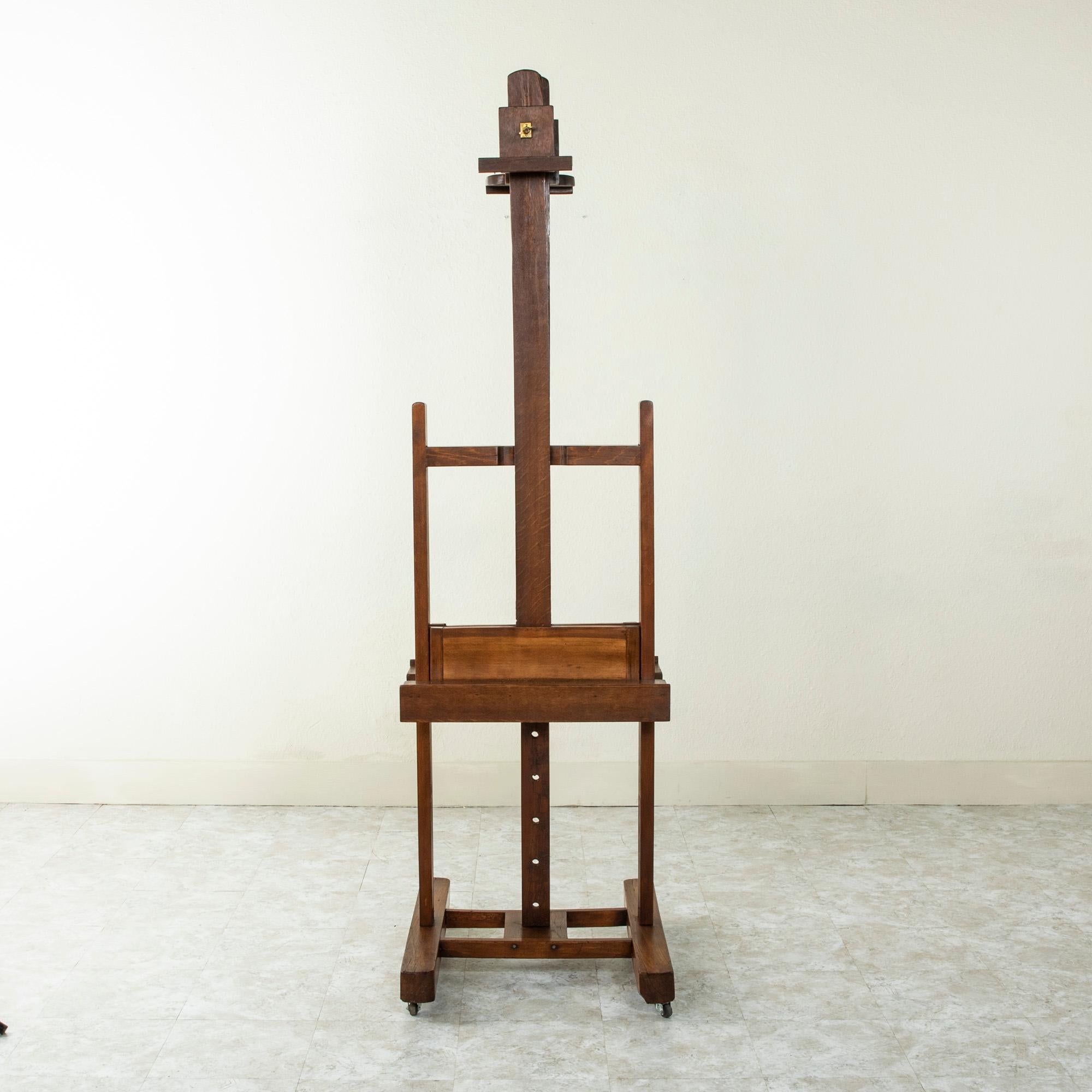 This large French oak and walnut floor easel from the late nineteenth century is double faced, allowing for display of a painting on each side. An iron lever allows for an adjustable height of each tray ranging from 60.5 to 92.5 inches. The five