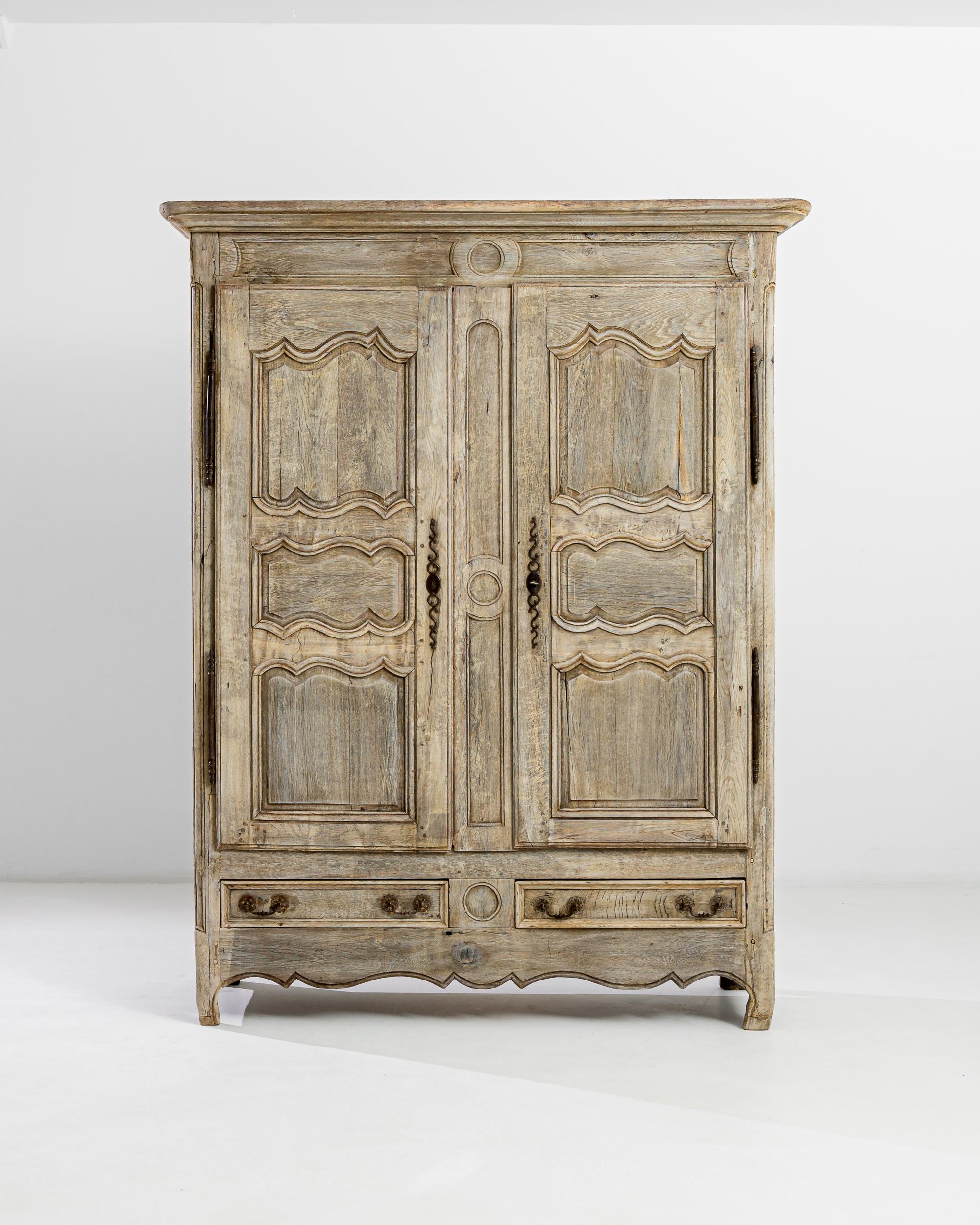 A 19th century oak armoire produced in France, this majestic wooden chest marries the picturesque to the elegant. Crowned by a molded top, the craftily carved front stands on tiptoed hooves, embellished by a scalloped apron. The ample four shelf