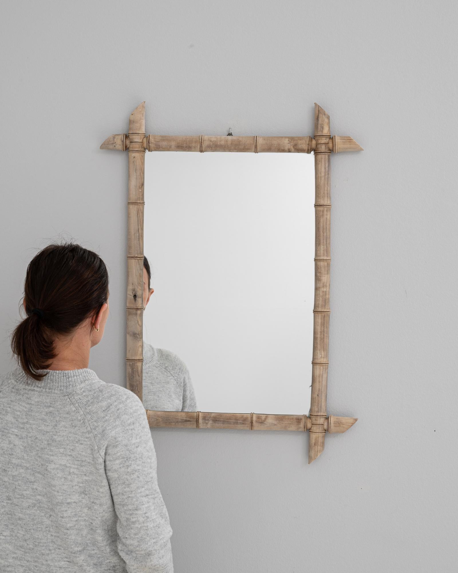 Ce miroir en chêne français du XIXe siècle est conçu dans un charmant style faux bambou, habilement sculpté pour imiter la structure segmentée et la texture naturelle du vrai bambou. Les extensions d'angle allongées et incurvées confèrent au cadre