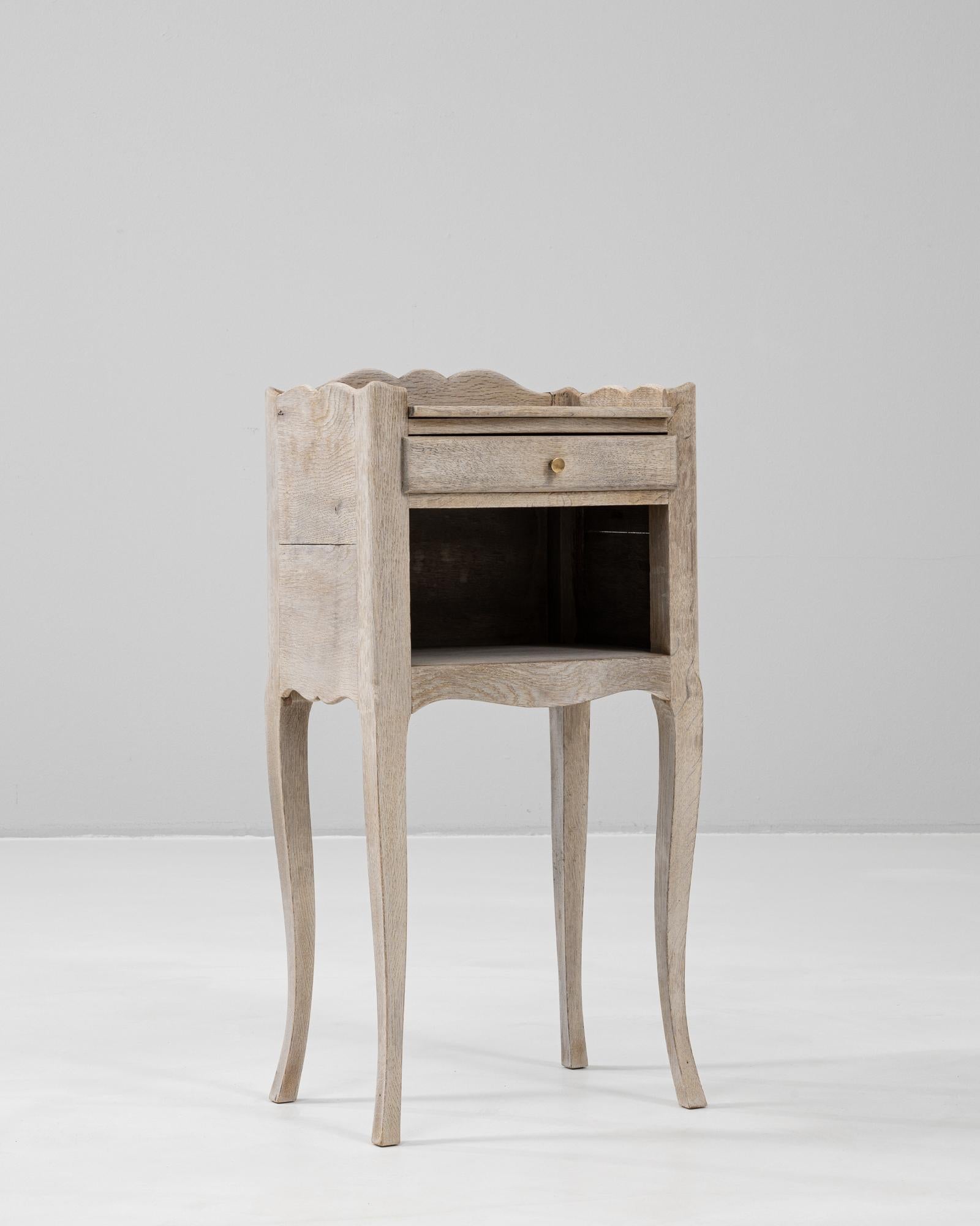 This 19th Century French Oak Bedside Table showcases the graceful simplicity of provincial craftsmanship. Constructed from solid oak with a soft, pale-toned finish, it features cabriole legs and gently scalloped edges along the apron and gallery,