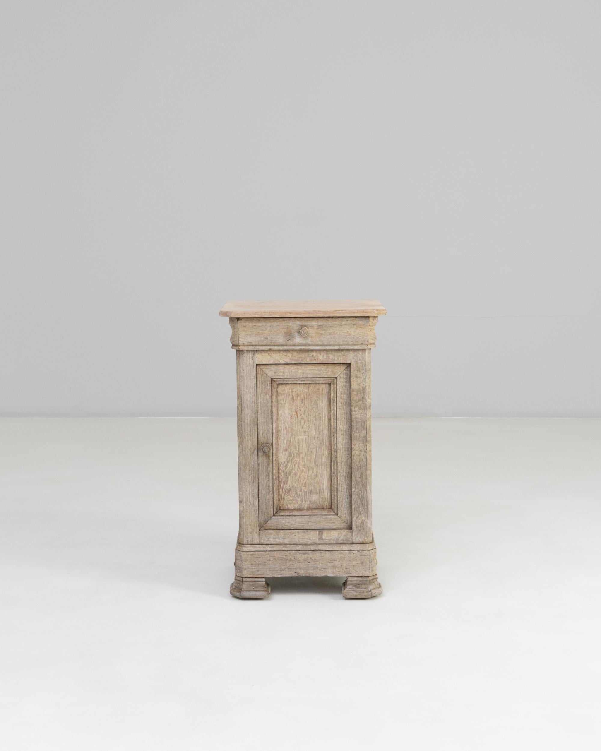 19th Century French Oak Bedside Table. This petite French bedside table showcases the timeless simplicity and craftsmanship of 19th-century provincial design. Built from solid oak with a naturally weathered patina, it features a single paneled door