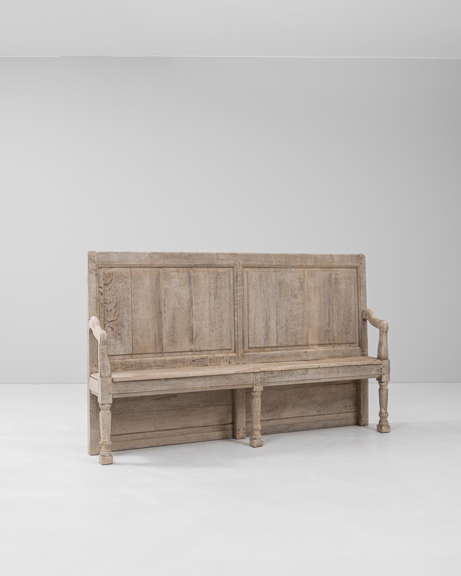 Ce banc en chêne français du XIXe siècle est un exemple frappant de l'artisanat provincial, alliant l'utilité à la forme sculpturale. Fabriqué en chêne massif, ce banc est doté d'un dossier haut et lambrissé et d'accoudoirs légèrement incurvés qui