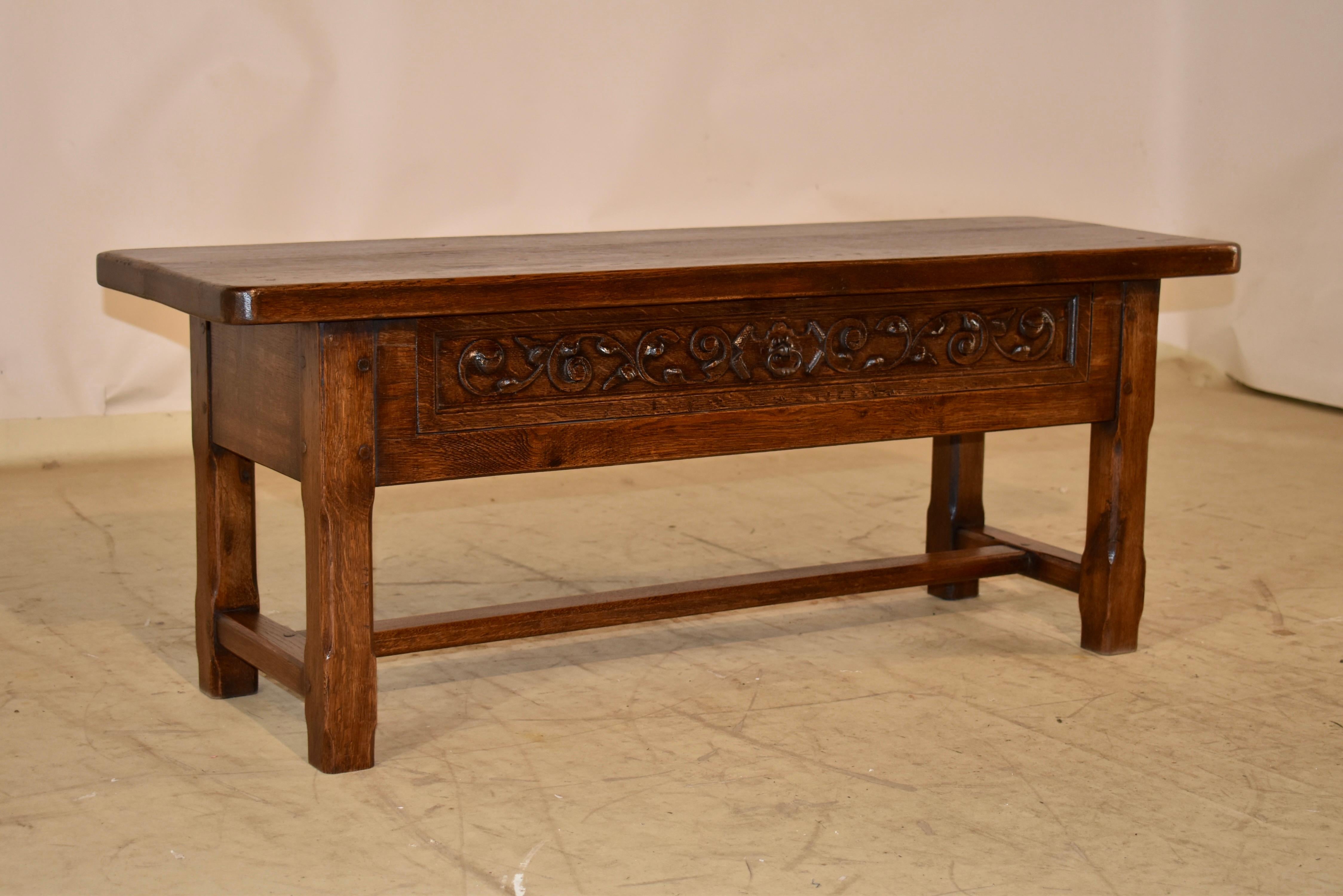 19th century oak bench from England.  The top is made from two thick planks with wonderful graining and patina.  The top follows down to a single drawer in the front, which has hand carved decoration on the drawer front, surrounded by a paneled
