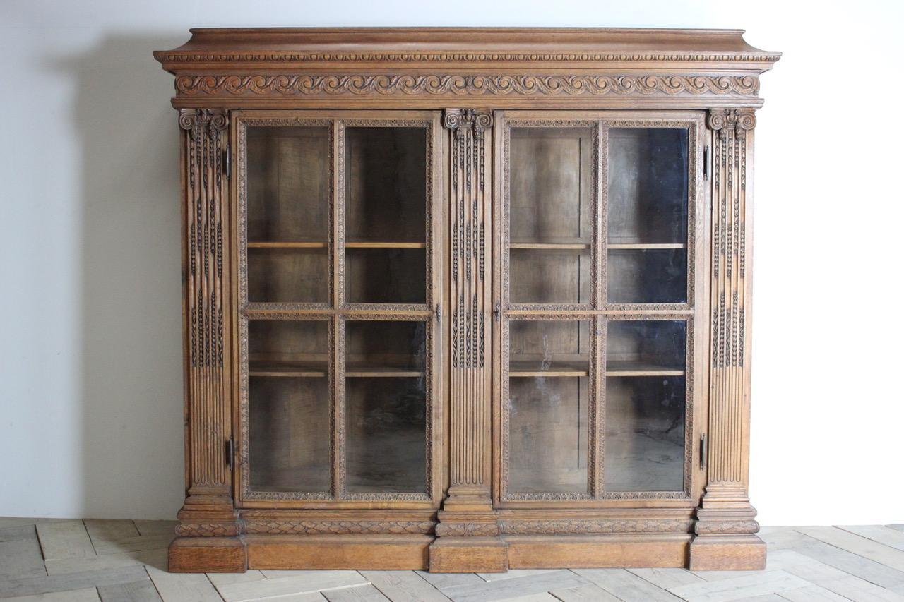 An imposing and elaborately carved French oak library bookcase that would make a statement in any setting, with glazed doors enclosing adjustable shelves, Grenobles, early 19th century.
 