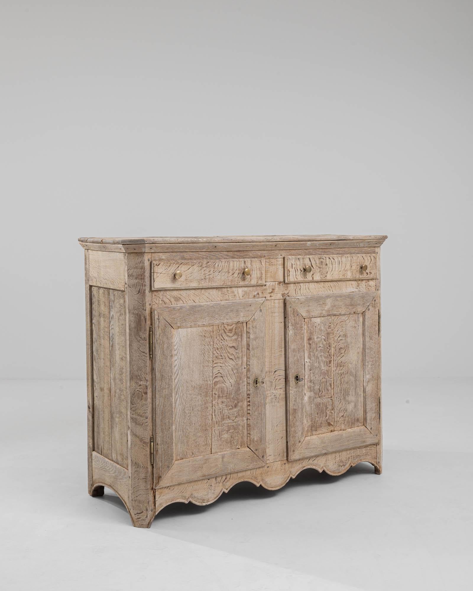 An oak buffet from 19th century, France. This wooden buffet – the finest expression of a wooden storage box– is composed with two paneled doors, an interior shelf, and two drawers fixed with brass pull knobs. A delicate bleaching process has been