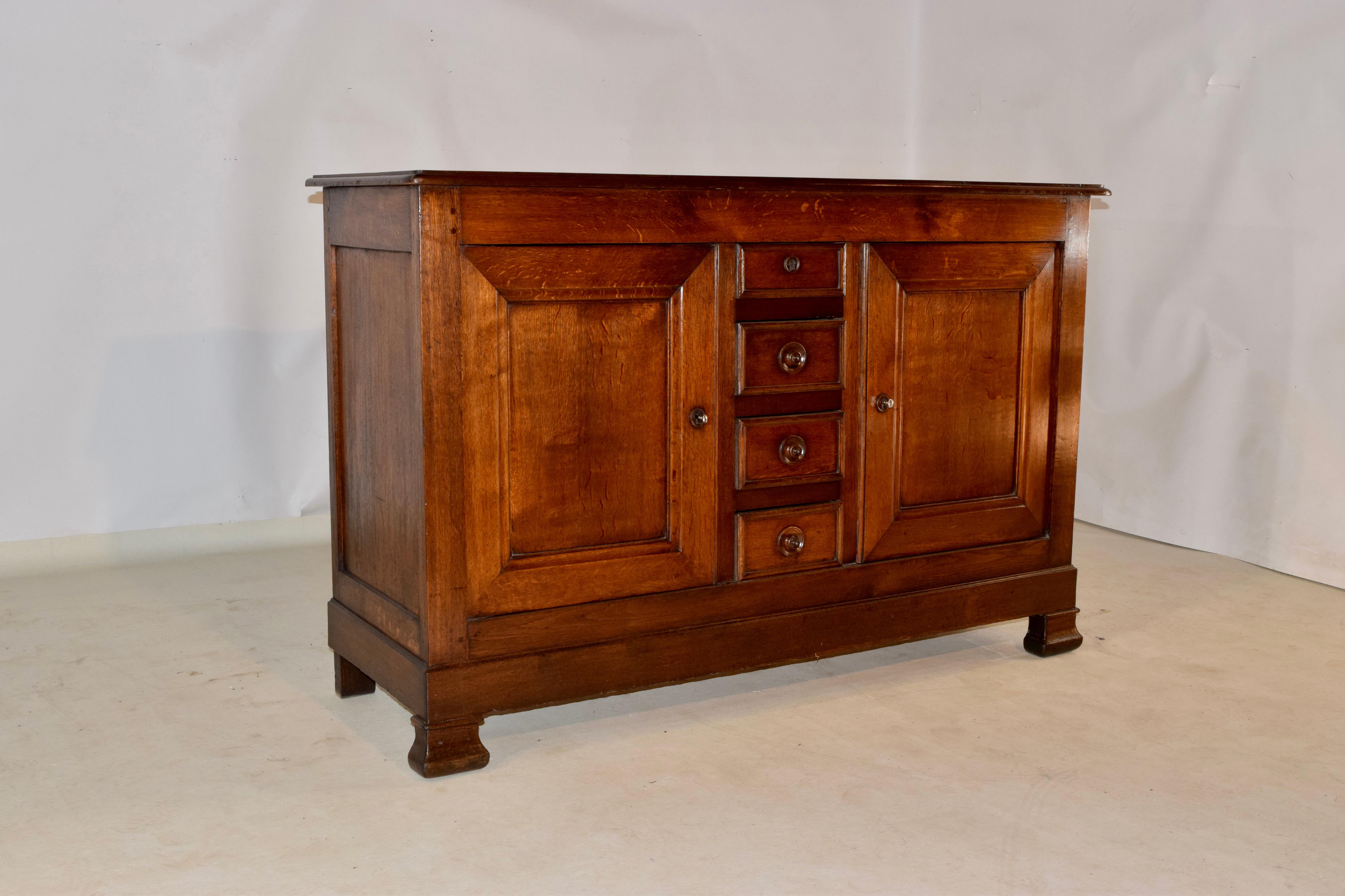 19th century oak buffet from France with a banded and beveled edge around the top, following down to simple paneled sides and four central drawers, all with molded edges and flanked by two paneled doors. The apron is simple and the piece is