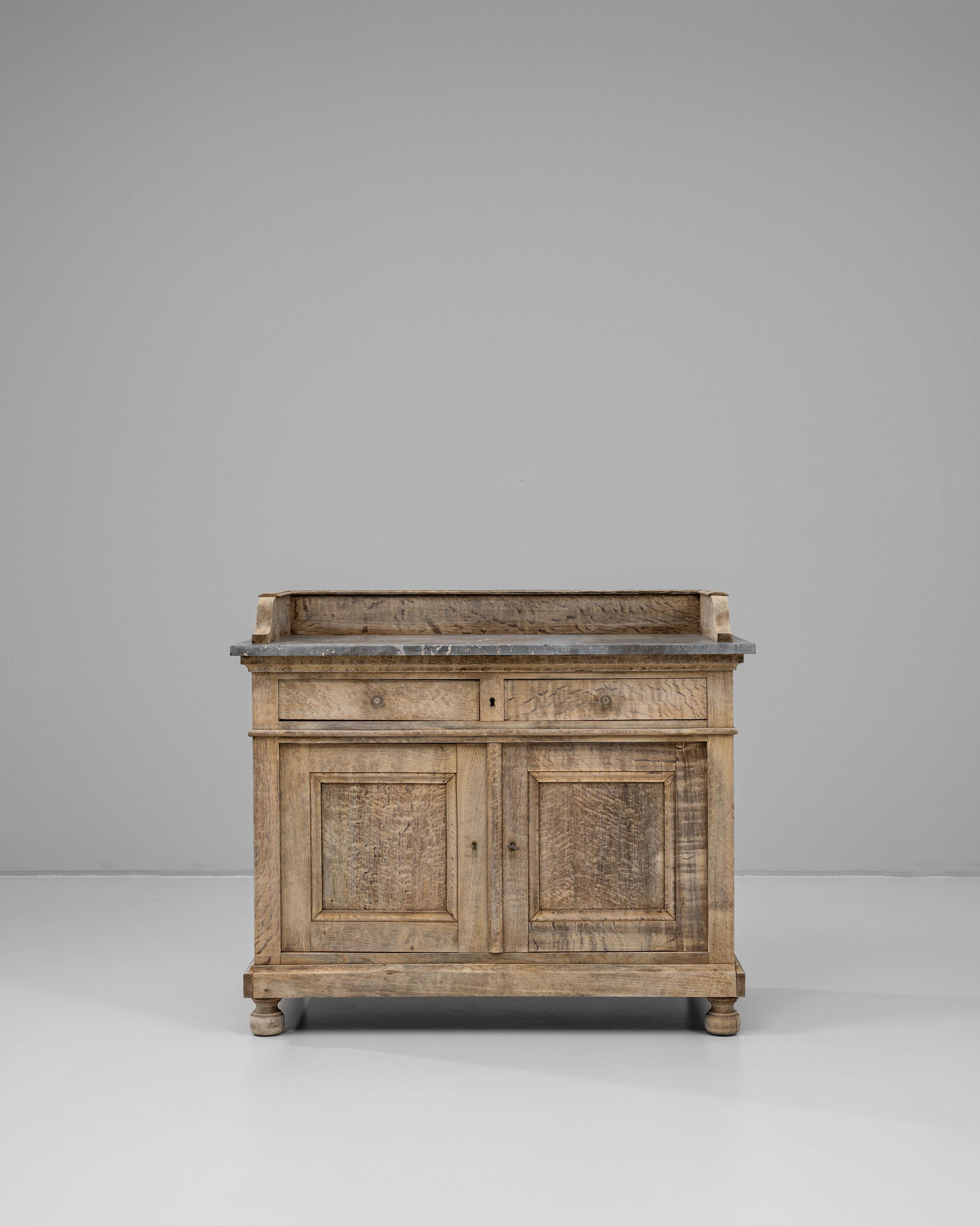 Questo buffet in quercia francese del XIX secolo con piano in marmo offre un equilibrio distinto tra utilità e sobria eleganza. Realizzato in rovere massiccio, il pezzo conserva una superficie splendidamente strutturata e consumata dal tempo che