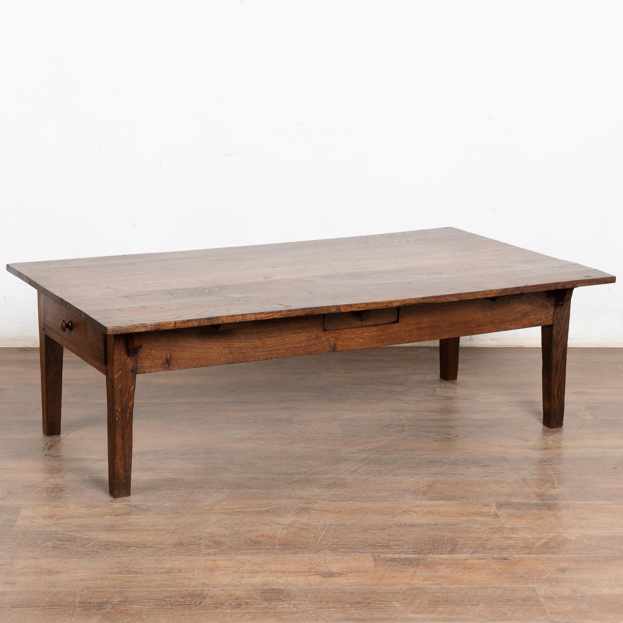 Tavolino in quercia francese del XIX secolo con quattro cassetti funzionali, due più grandi sulle estremità corte e due più piccoli al centro. La patina invecchiata evidenzia generazioni di utilizzo. Lungo la parte superiore sono visibili vecchie