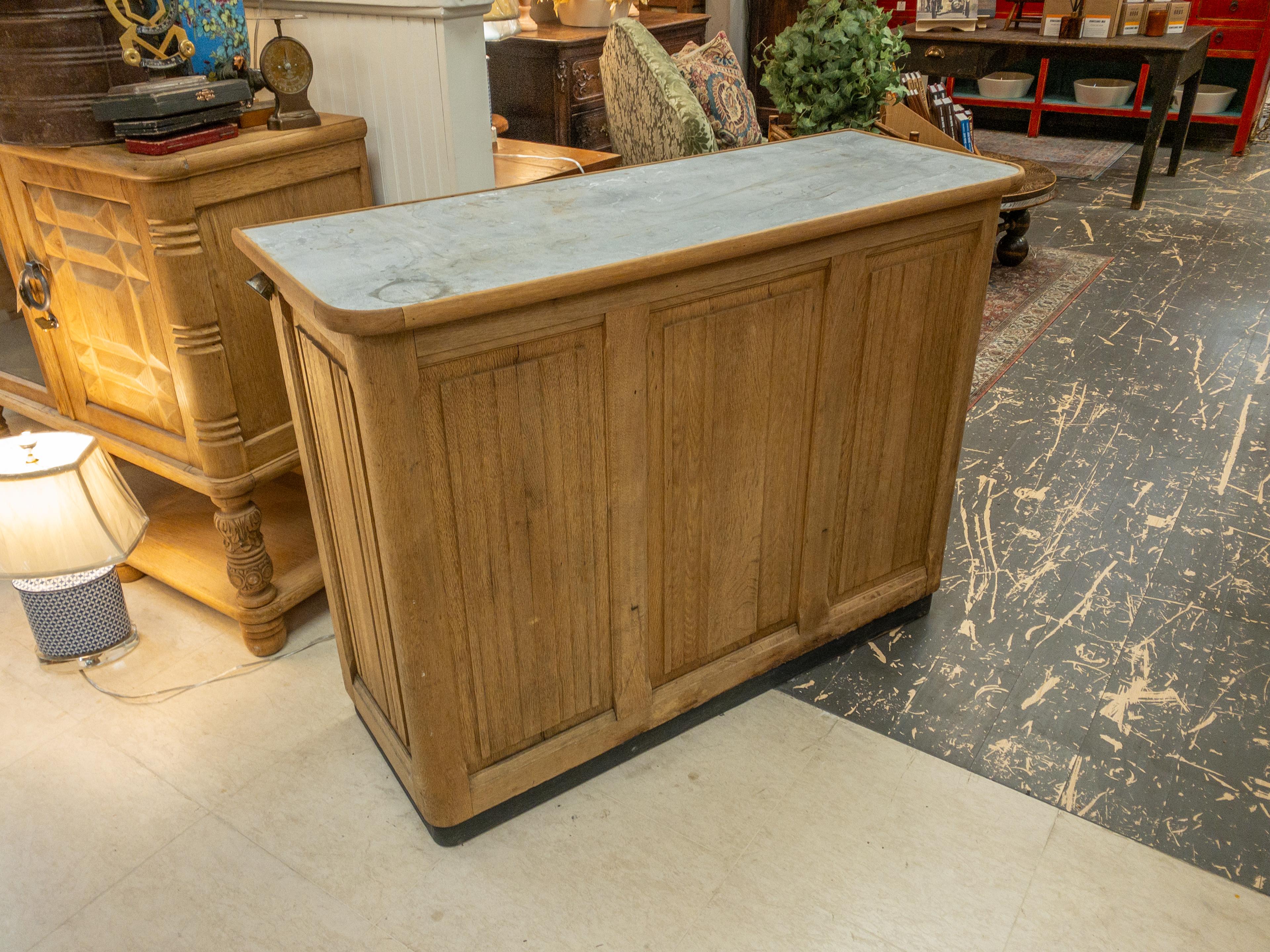 The 19th Century French Oak Counter exudes timeless charm with its rich history and elegant craftsmanship. Standing proudly with a sturdy oak frame, it boasts a metal top, adding a touch of industrial sophistication. Behind the counter, a single